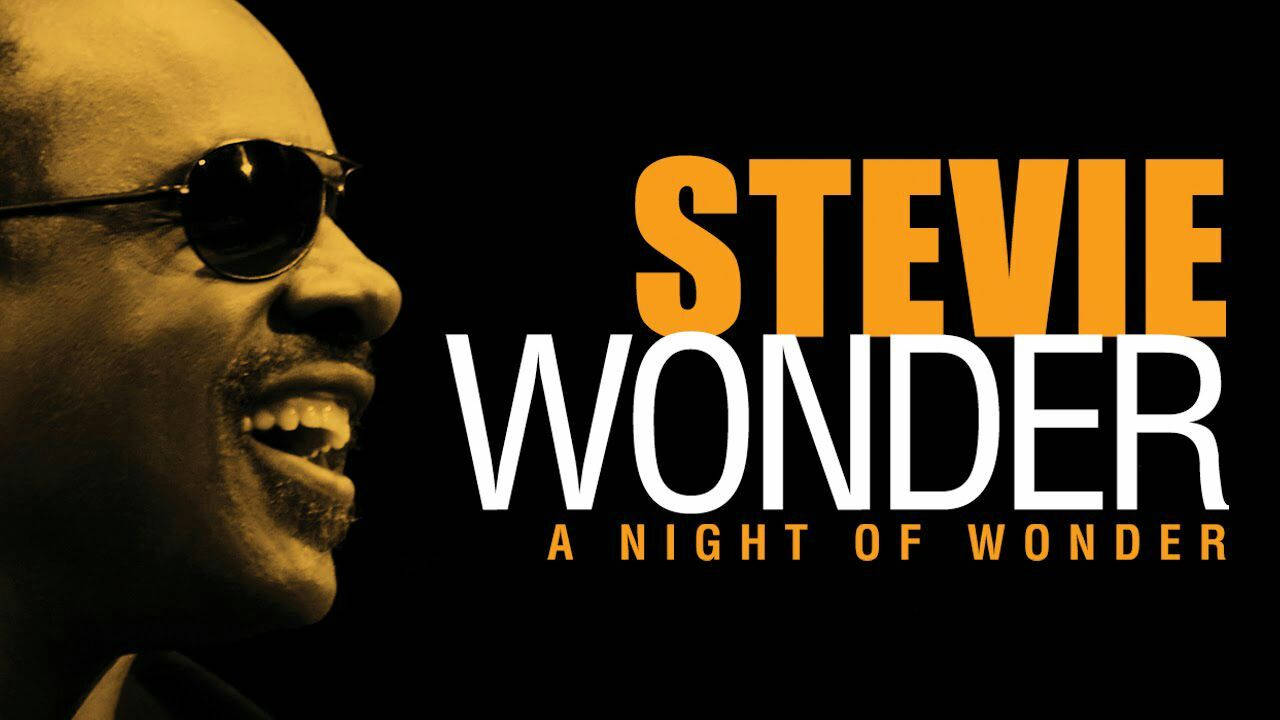 音樂 桌布 壁紙 — Stevie Wonder 戴著太陽眼鏡，側面微笑，背景為黑色，帶有粗體橙色和白色文字。