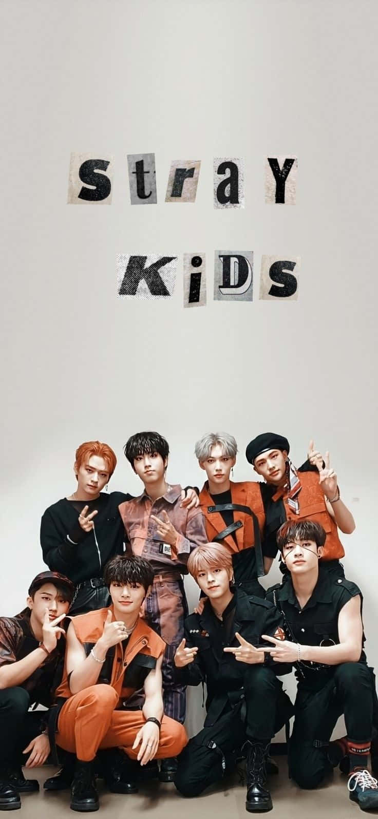桌布 壁紙 — Stray Kids 自信地穿著橙色和黑色服裝，在素牆前擺姿勢，上方用鏤空字母拼出他們的名字。