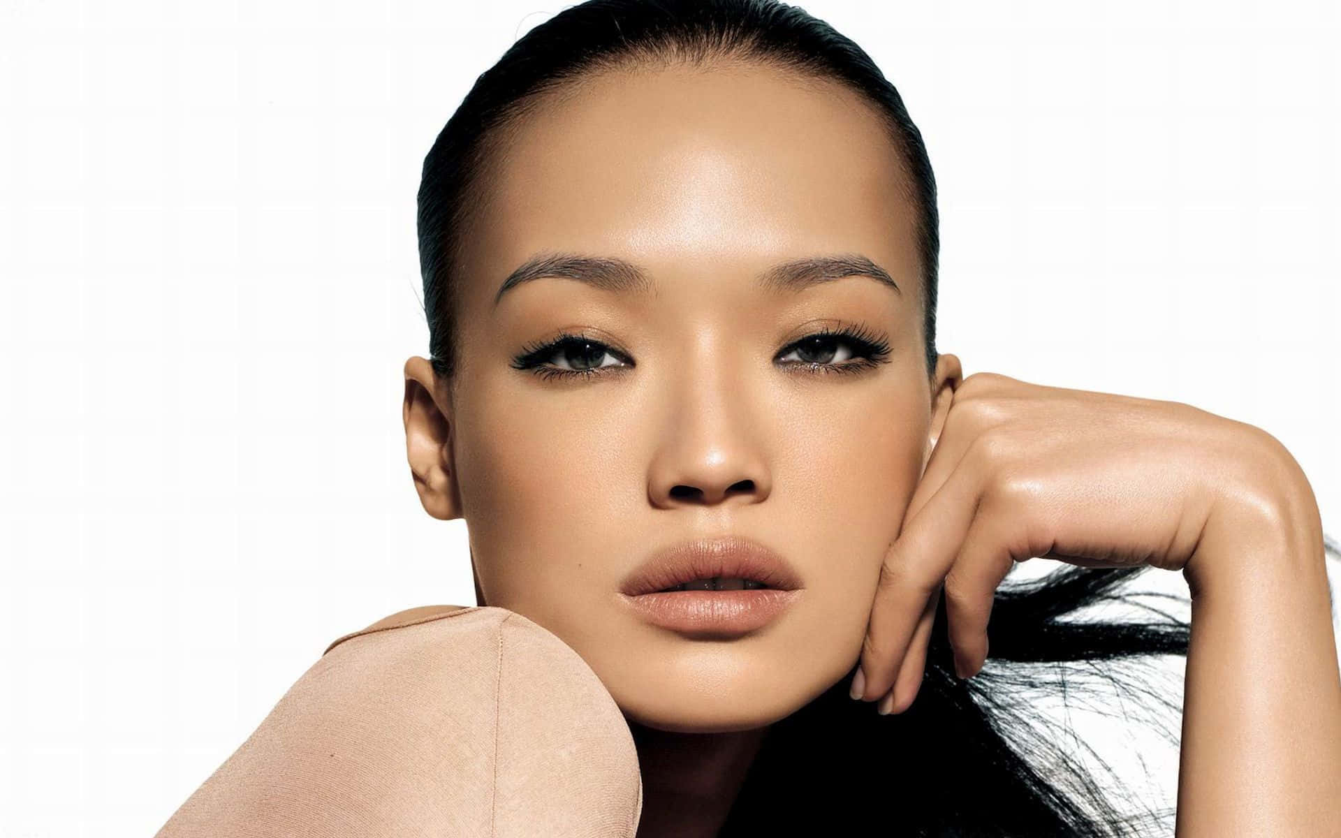 Shu Qi 桌布 壁紙 — 一幅引人注目的肖像，一位擁有光滑黑髮和大膽妝容的女性，在純白背景下直視鏡頭。
