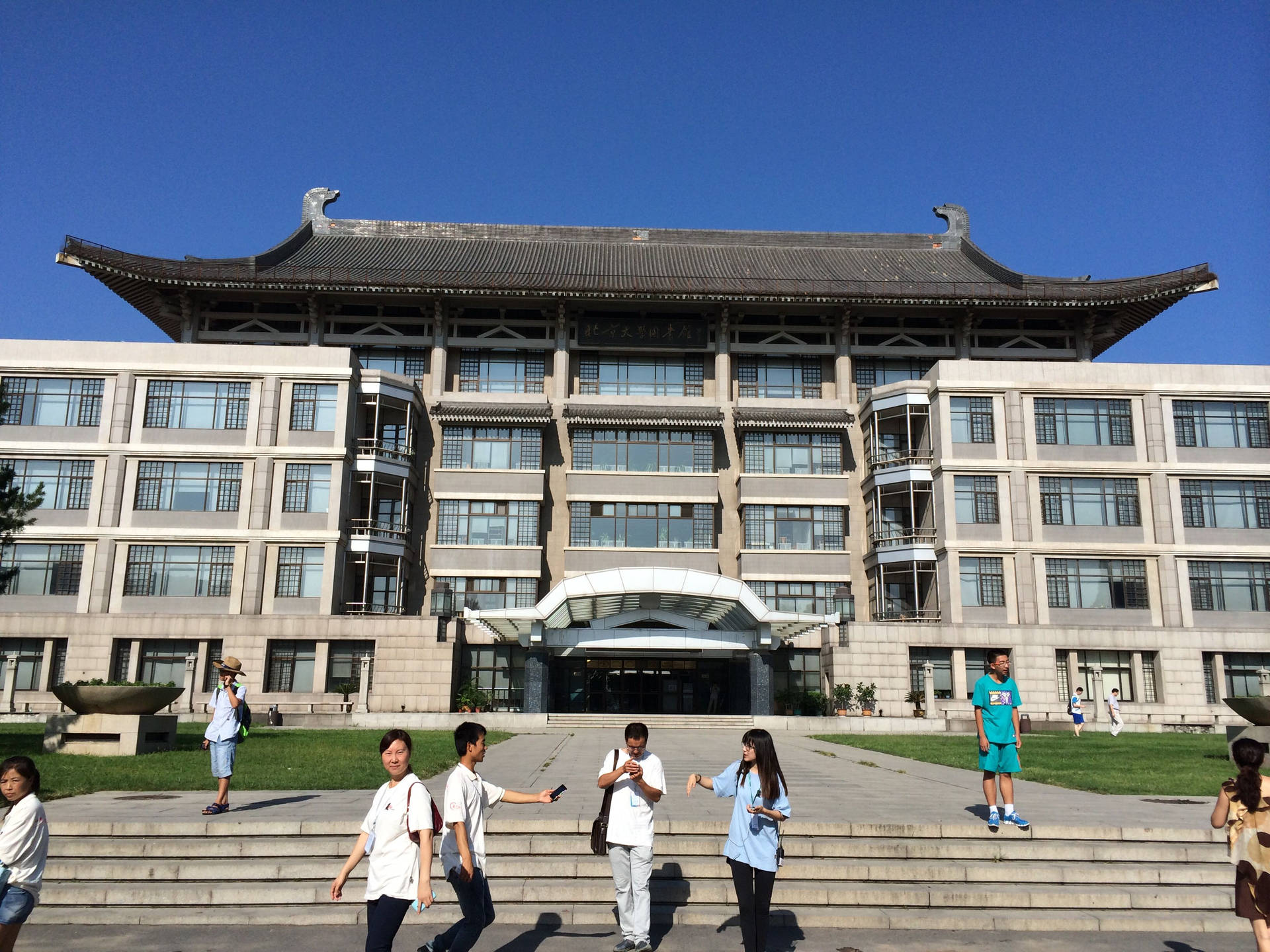 學生在陽光明媚的日子裡，在一棟大型大學建築前的台階上行走。 — 中國 壁紙