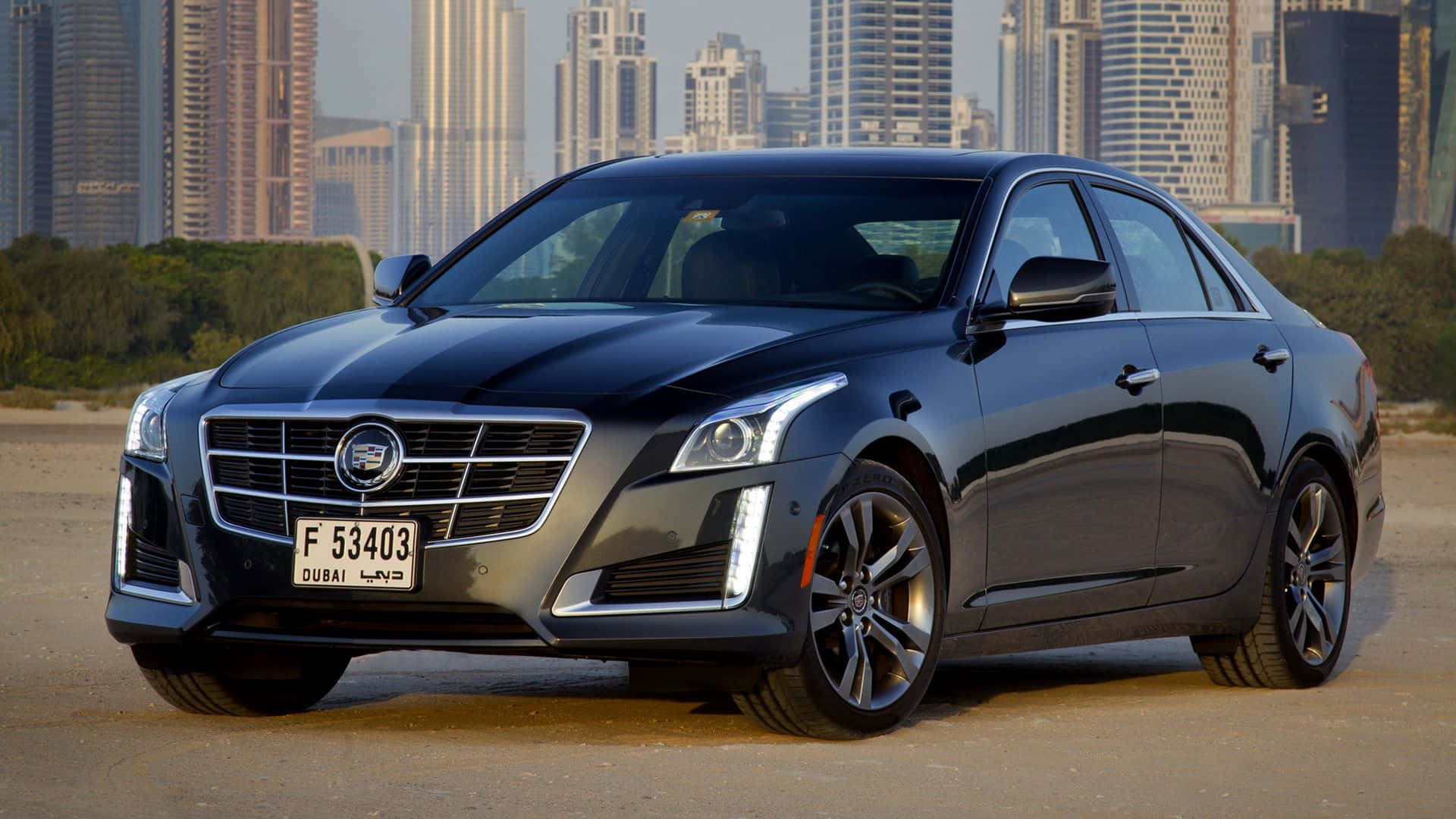 Cadillac Cts 桌布 壁紙 — 一輛時尚的黑色凱迪拉克轎車停在沙地上，背後是杜拜高聳的摩天大樓，在朦朧的天空下升起。