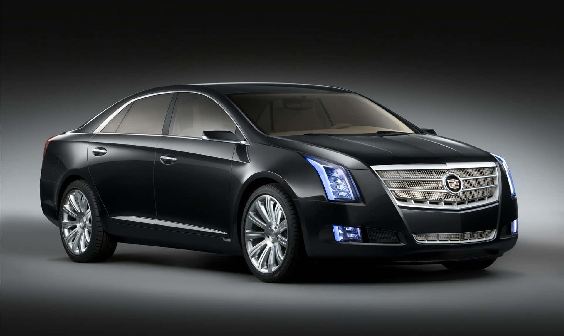 Cadillac Xts 桌布 壁紙 — 一輛時尚的黑色凱迪拉克轎車，帶有發光的藍色頭燈和鍍鉻裝飾，在深色漸變工作室背景前擺拍。