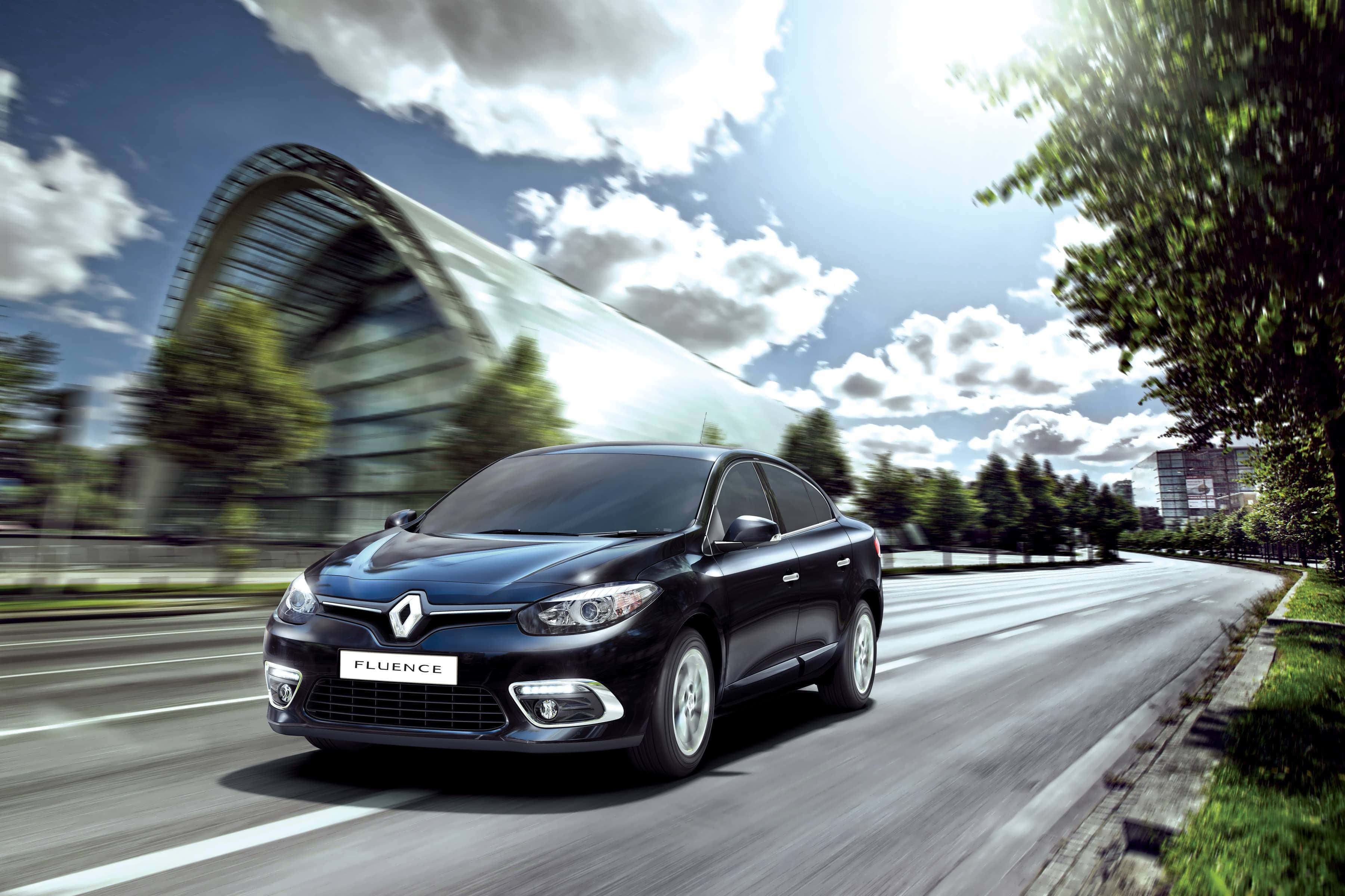 Renault Fluence 桌布 壁紙 — 一輛時尚的黑色雷諾Fluence在陽光明媚的城市道路上飛馳，帶有動態模糊效果，背景是現代玻璃建築。