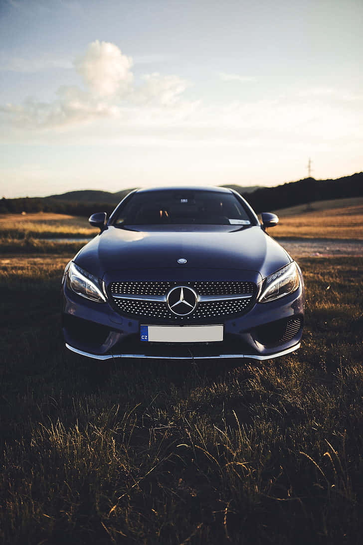 Mercedes Benz Cls-class 桌布 壁紙 — 一輛時尚的深藍色賓士轎車停泊在日落時分的金色田野中，背景是連綿起伏的山丘。