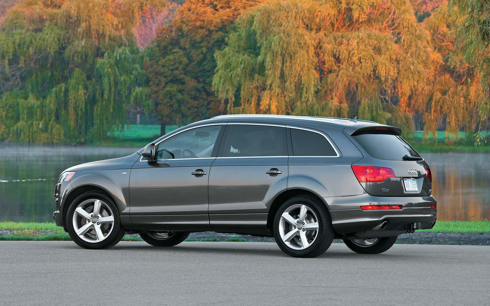 Audi Q7 桌布 壁紙 — 一輛時尚的銀色奧迪Q7旅行車停在霧氣瀰漫的湖邊，秋天的樹木倒映在水中。