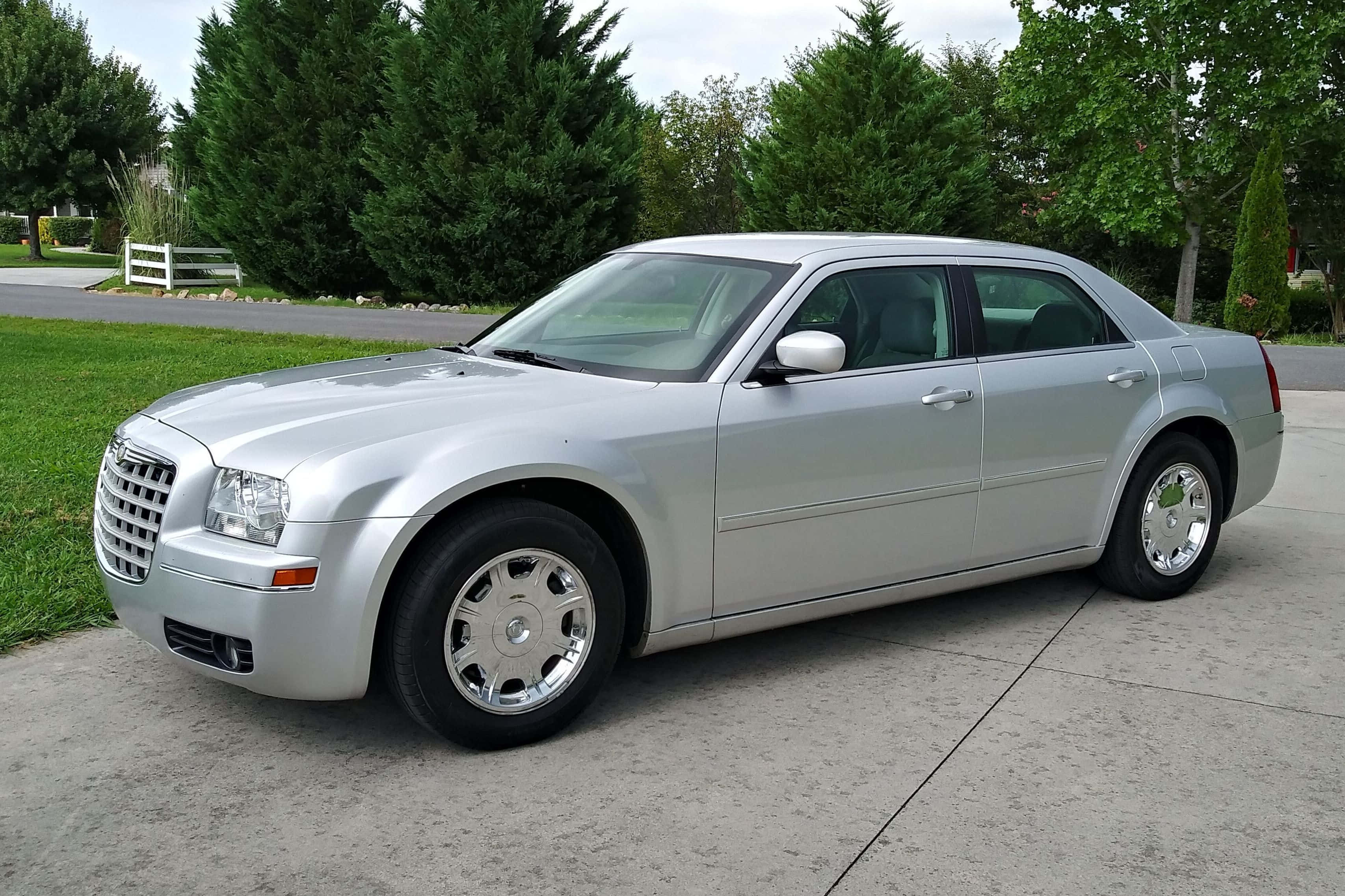 Chrysler 300 桌布 壁紙 — 一輛時尚的銀色Chrysler 300轎車停在混凝土車道上，背景有綠樹和草地。