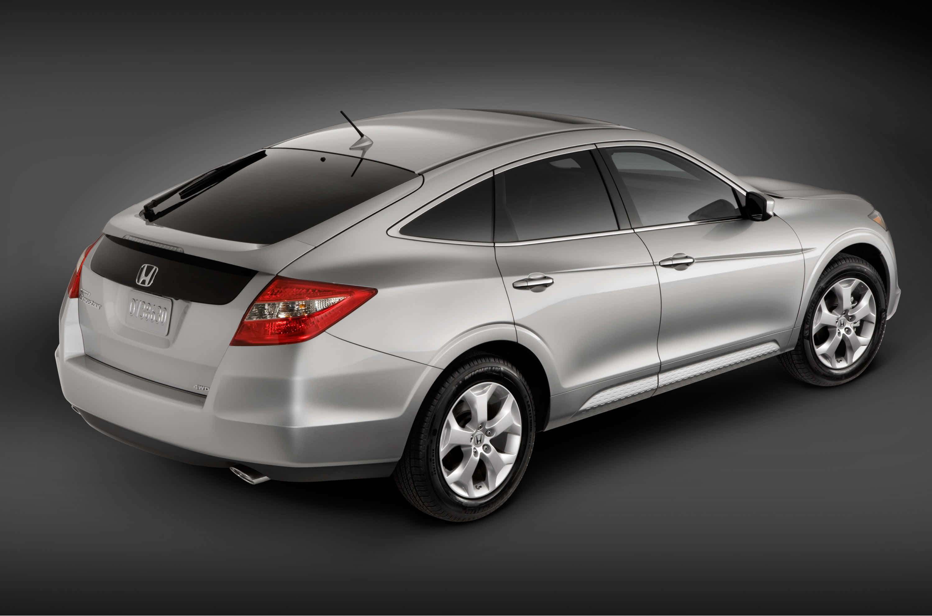 Honda Crosstour 桌布 壁紙 — 一輛時尚的銀色本田雅閣混合動力轎車，在深灰色背景下的攝影棚拍攝中從後方四分之三角度展示。