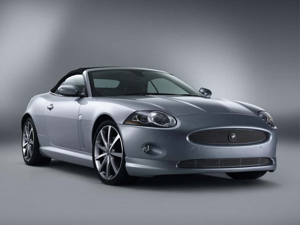 Jaguar Xk 桌布 壁紙 — 一輛時尚的銀色積架XK8敞篷車配黑色軟頂，在漸變灰色工作室背景前擺放。