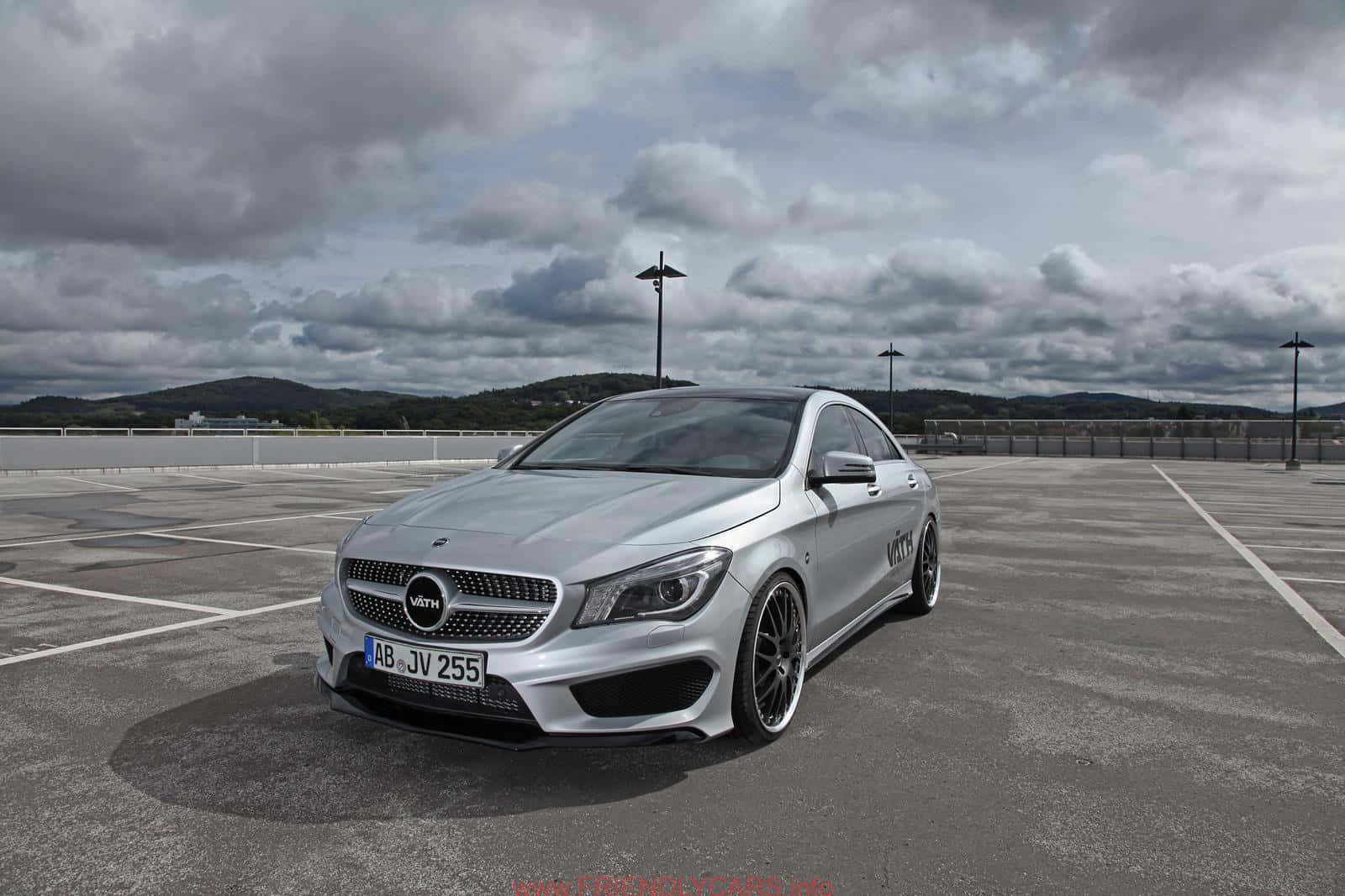 Mercedes Benz Cla-class 桌布 壁紙 — 一架時尚的銀色Mercedes-AMG CLA45停放在空蕩蕩的瀝青停車場，上方是戲劇性的多雲天空。