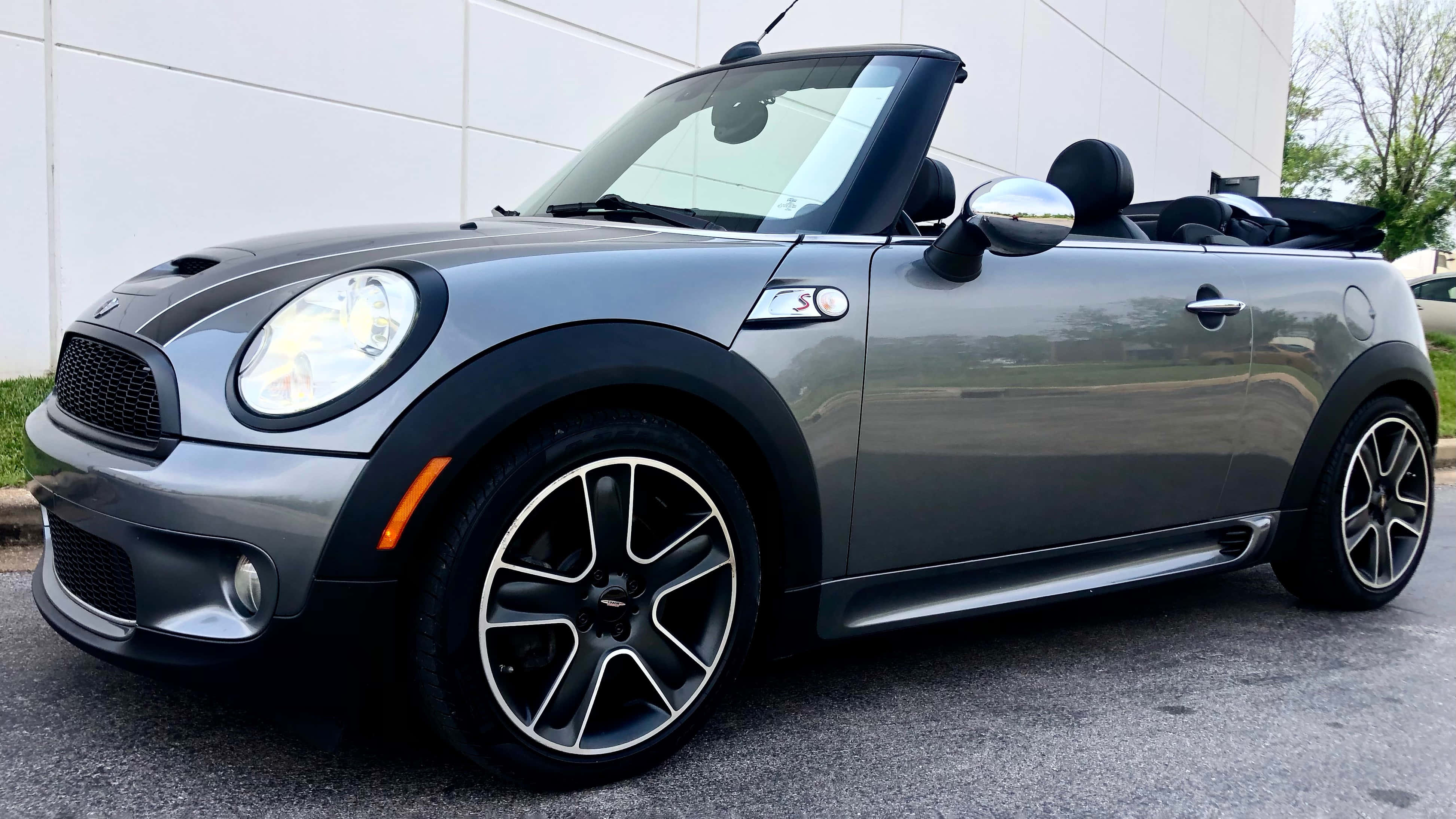 Mini Cooper S Convertible 桌布 壁紙 — 一架時尚的銀色MINI Cooper敞篷車停在柏油路上，背景有白色建築物和綠色樹木。