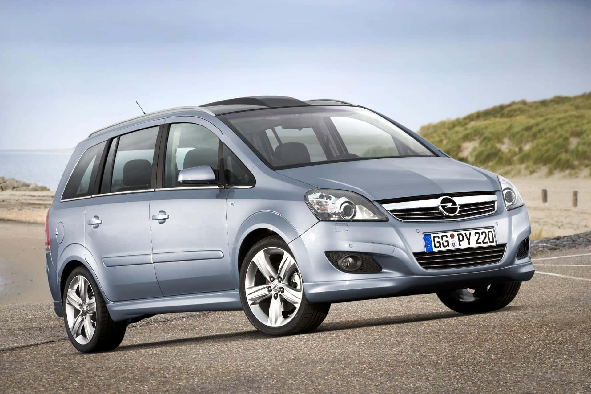 Opel Zafira 桌布 壁紙 — 一輛時尚的銀色歐寶Zafira停泊在沿海公路上，背景有沙丘和海洋。