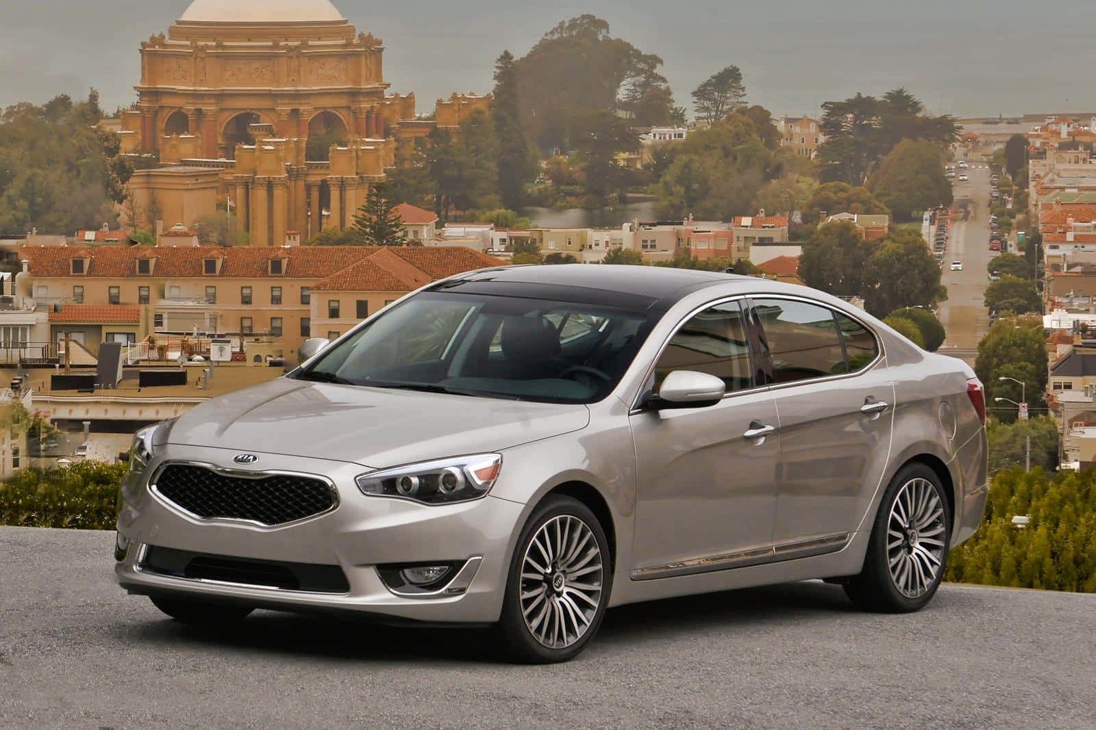 Kia Cadenza 桌布 壁紙 — 一輛時尚的銀色轎車停泊在山上，俯瞰著城市景觀，背景是一座歷史悠久的圓頂建築。