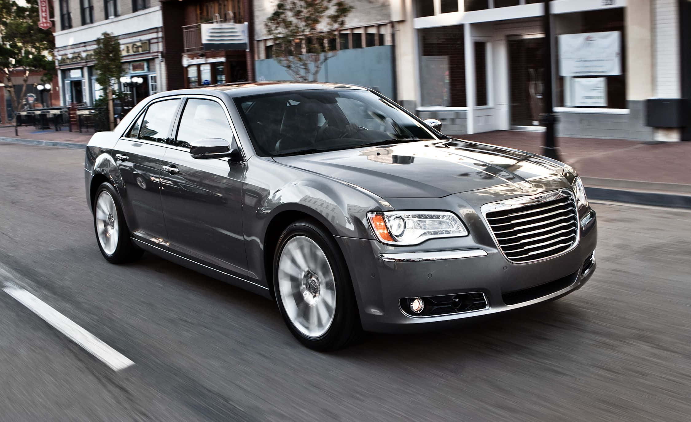Chrysler 300 桌布 壁紙 — 一輛時尚的銀色轎車在城市的街道上飛馳，動態模糊傳達了充滿活力的城市運動。