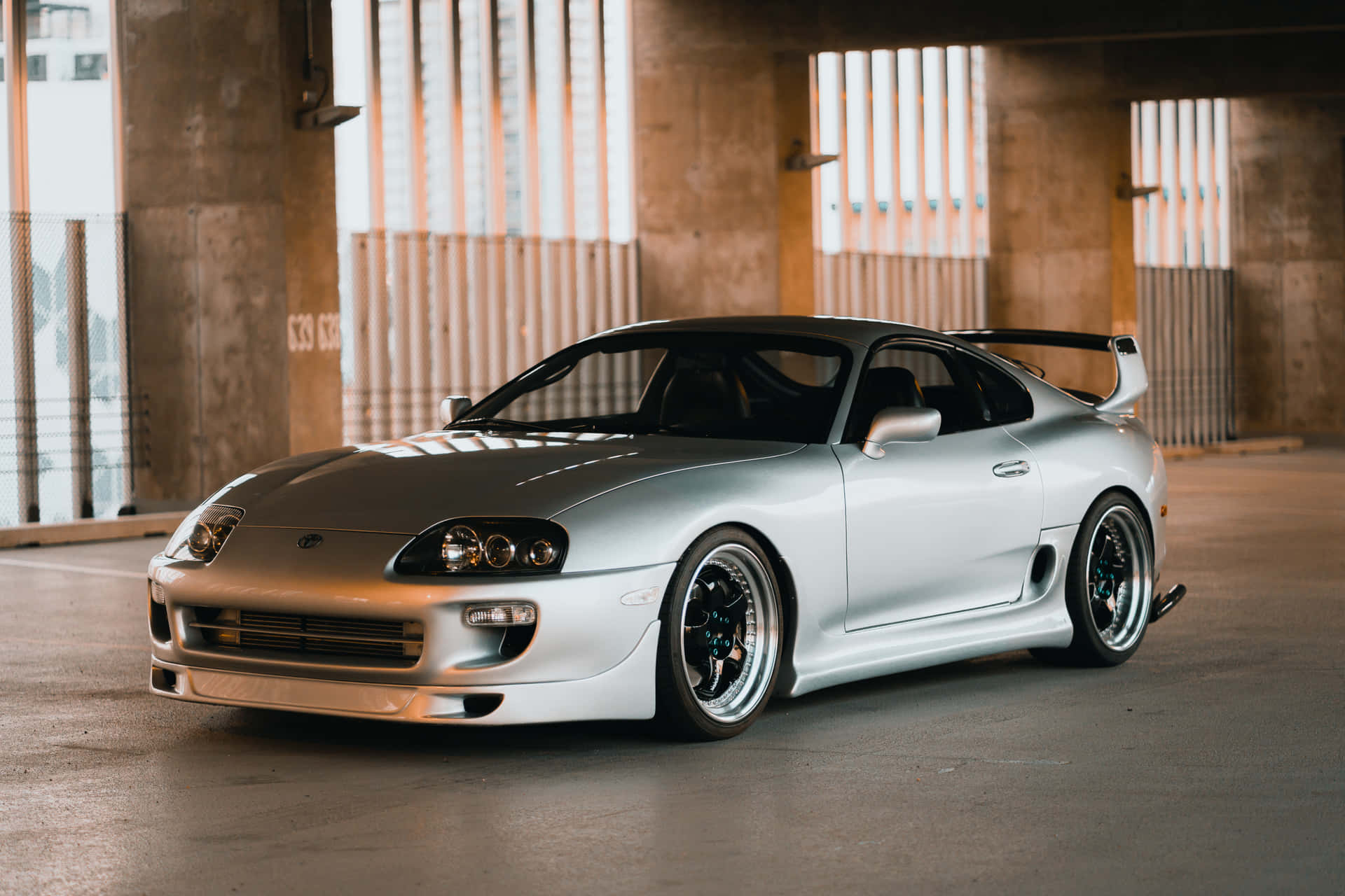 銀色豐田Supra跑車停放在帶有垂直百葉窗的混凝土天橋下。 — Toyota Supra 壁紙