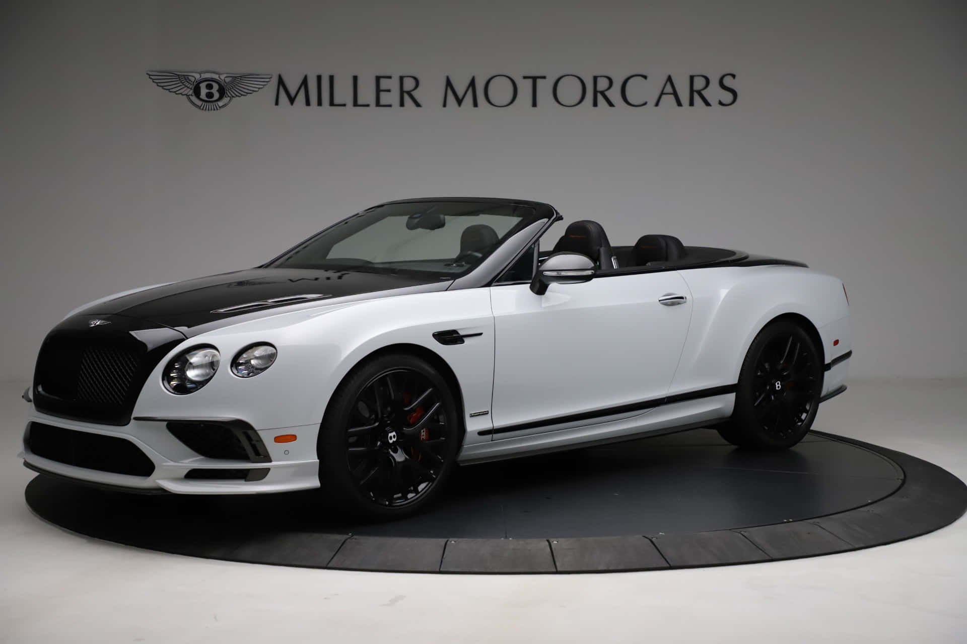 Bentley Continental Supersports 桌布 壁紙 — 一輛時尚的白色和黑色賓利敞篷車搭配黑色輪圈，在攝影棚燈光下展示於圓形平台上。