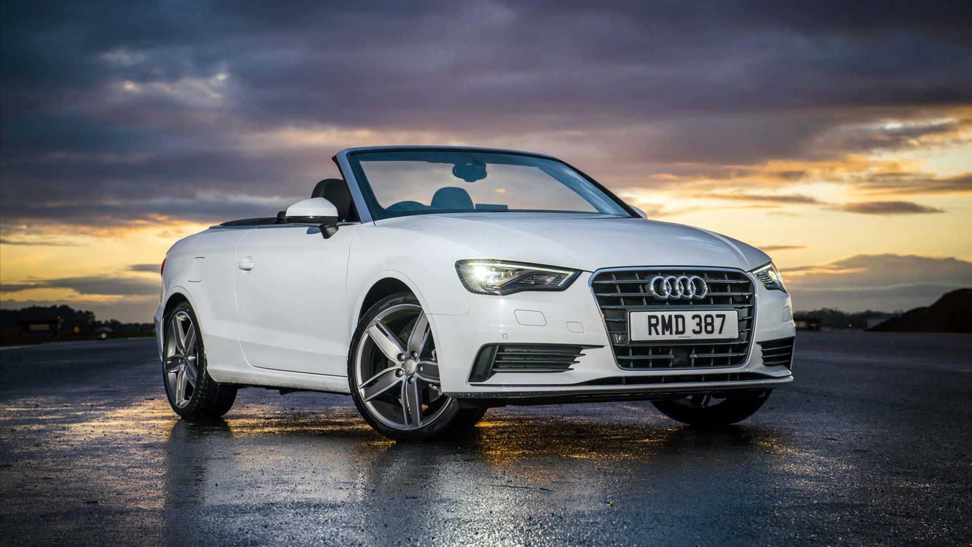 Audi A3 桌布 壁紙 — 一輛時尚的白色奧迪敞篷車在橙紫色雲彩的戲劇性日落天空下閃閃發光。