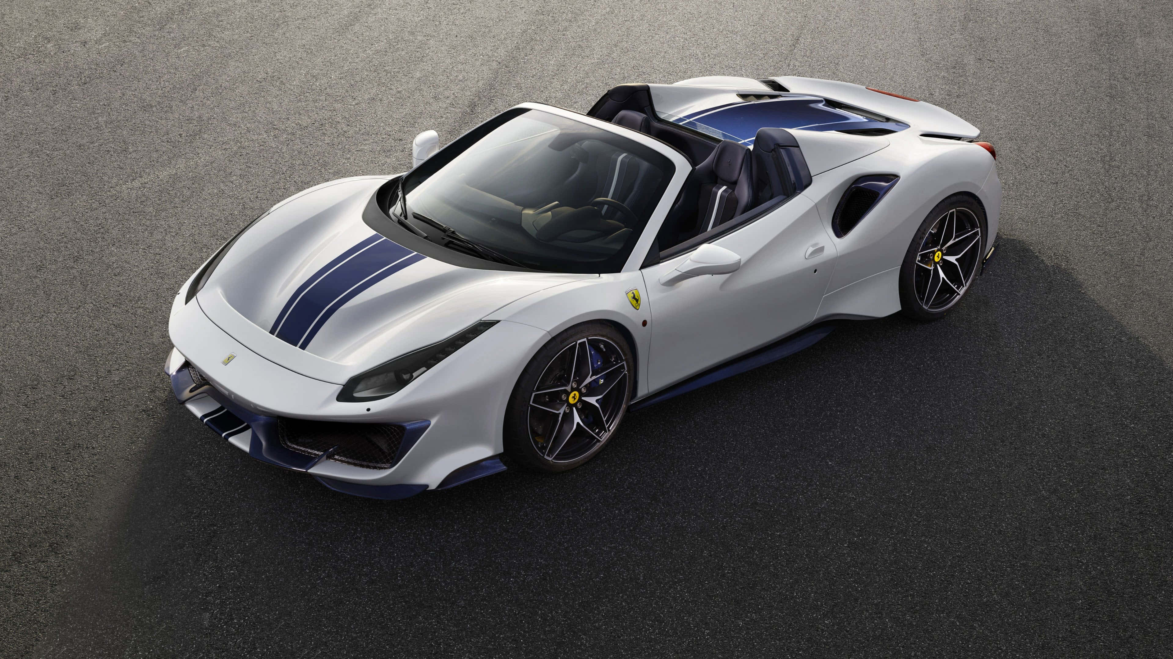 Ferrari 488 Spider 桌布 壁紙 — 一輛時尚的白色法拉利敞篷車，帶有藍色賽車條紋，停在灰色瀝青路面上。