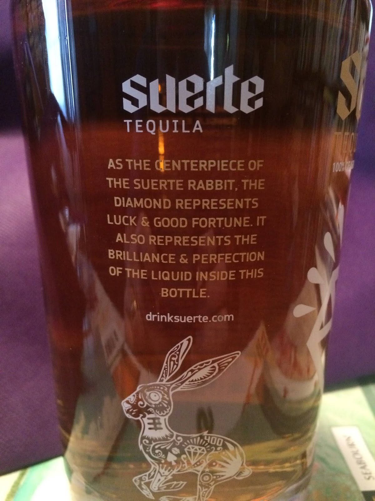標誌 桌布 壁紙 — Suerte Tequila 酒瓶特寫，展示其華麗的兔子設計和品牌文字，背景為紫色。