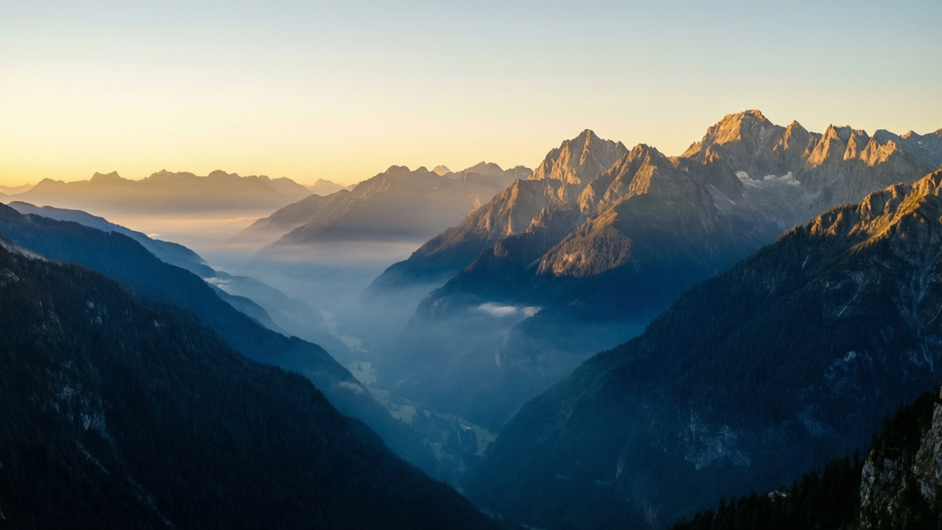Outlook of Misty Mountain Sunrise 壁紙 — 陽光將崎嶇的山峰染成金色，薄霧在下方深邃的森林山谷中翻滾。