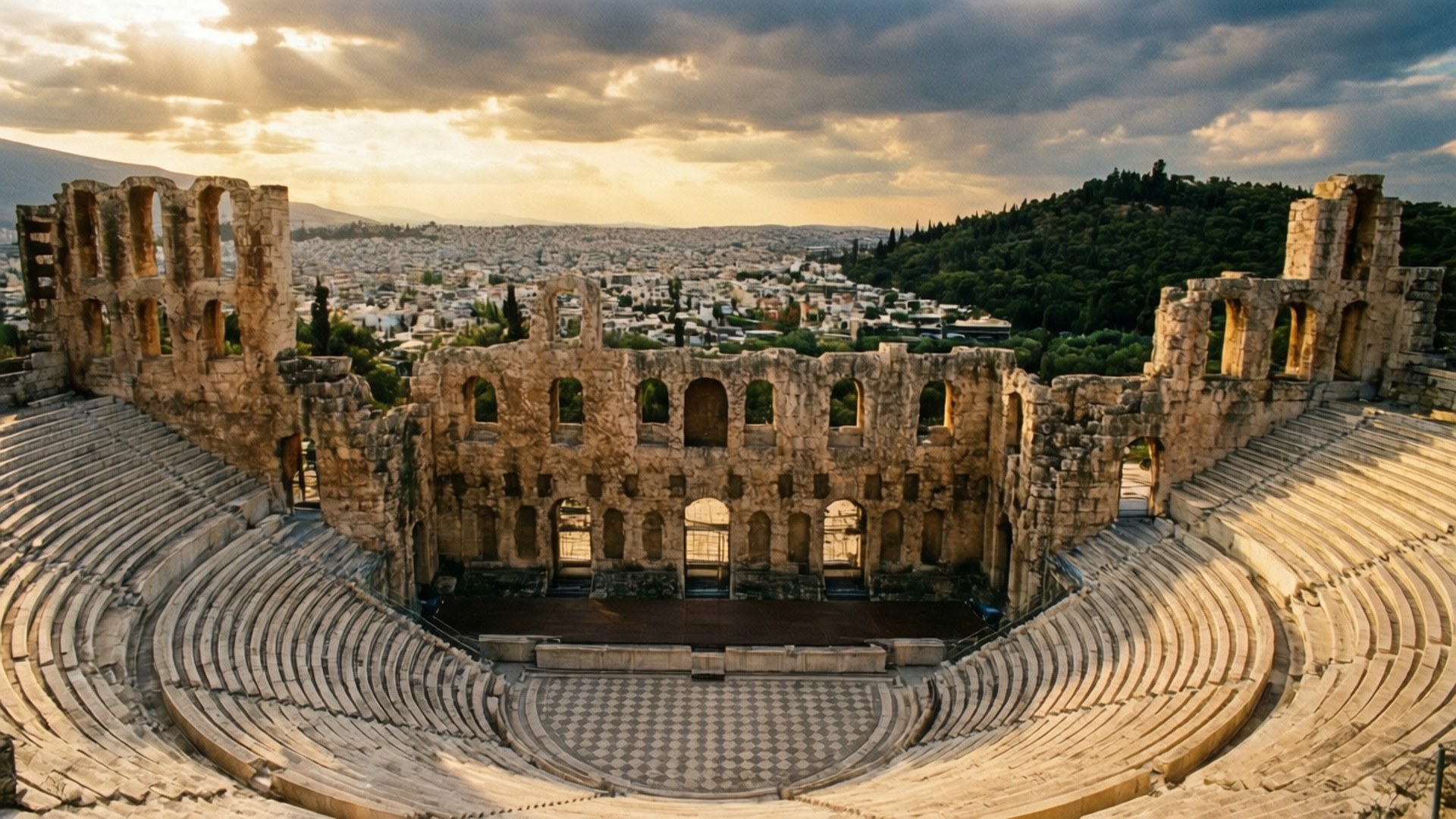 Herodes Atticus Theatre 壁紙 — 陽光穿過暴風雲，照亮了雅典廢墟劇院的古老石座和柱子，俯瞰著城市。