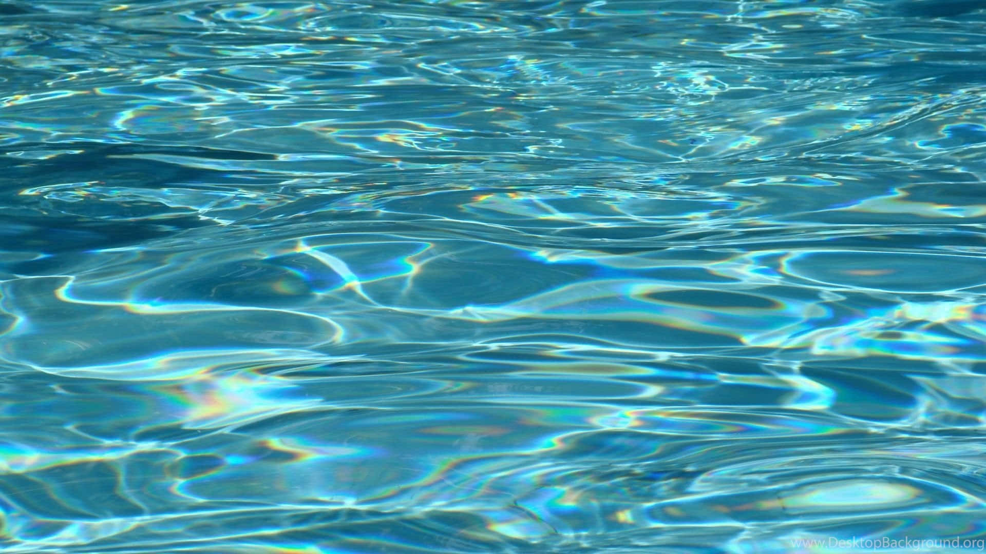  壁紙 — 陽光在漣漪的藍色水面上舞動，在水面形成閃爍的彩虹倒影。