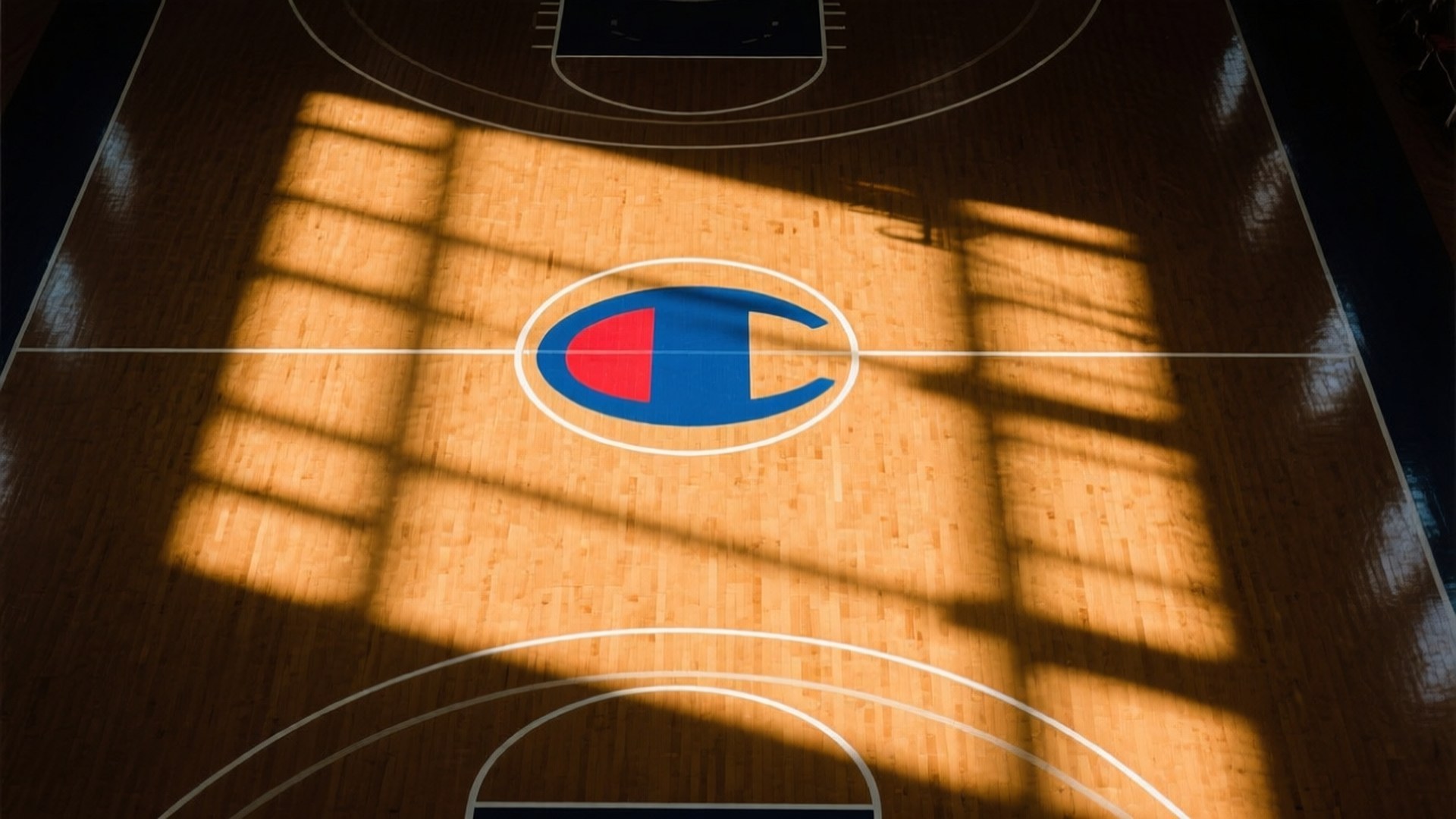 Basketball Court Champion Logo 壁紙 — 陽光穿過窗戶，在中央帶有Champion標誌的拋光木製籃球場上投射出條紋陰影。