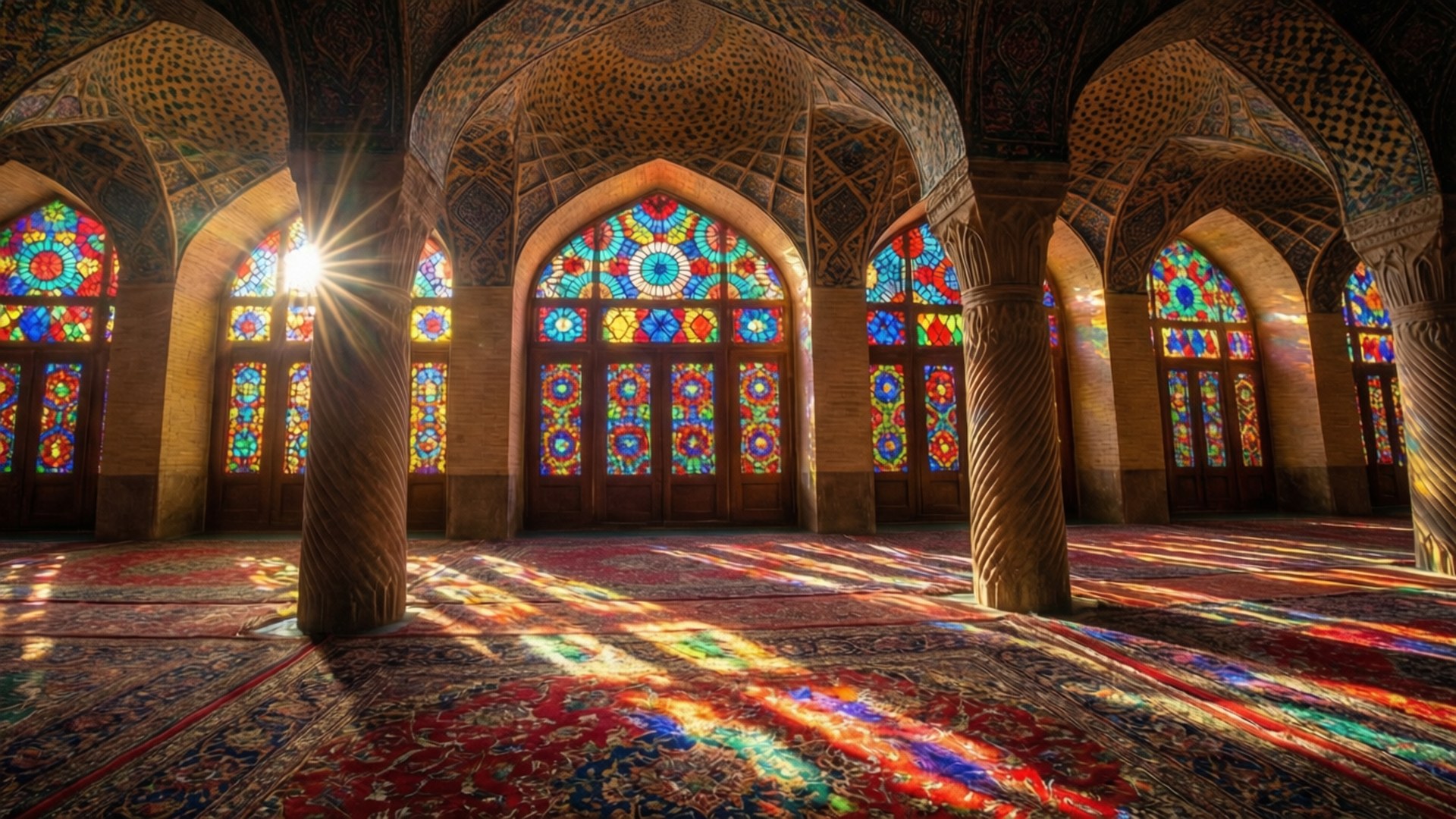 Rainbow Mosque Interior 壁紙 — 陽光穿過鮮豔的彩繪玻璃窗，在華麗的波斯祈禱地毯上投射出色彩斑斕的圖案。