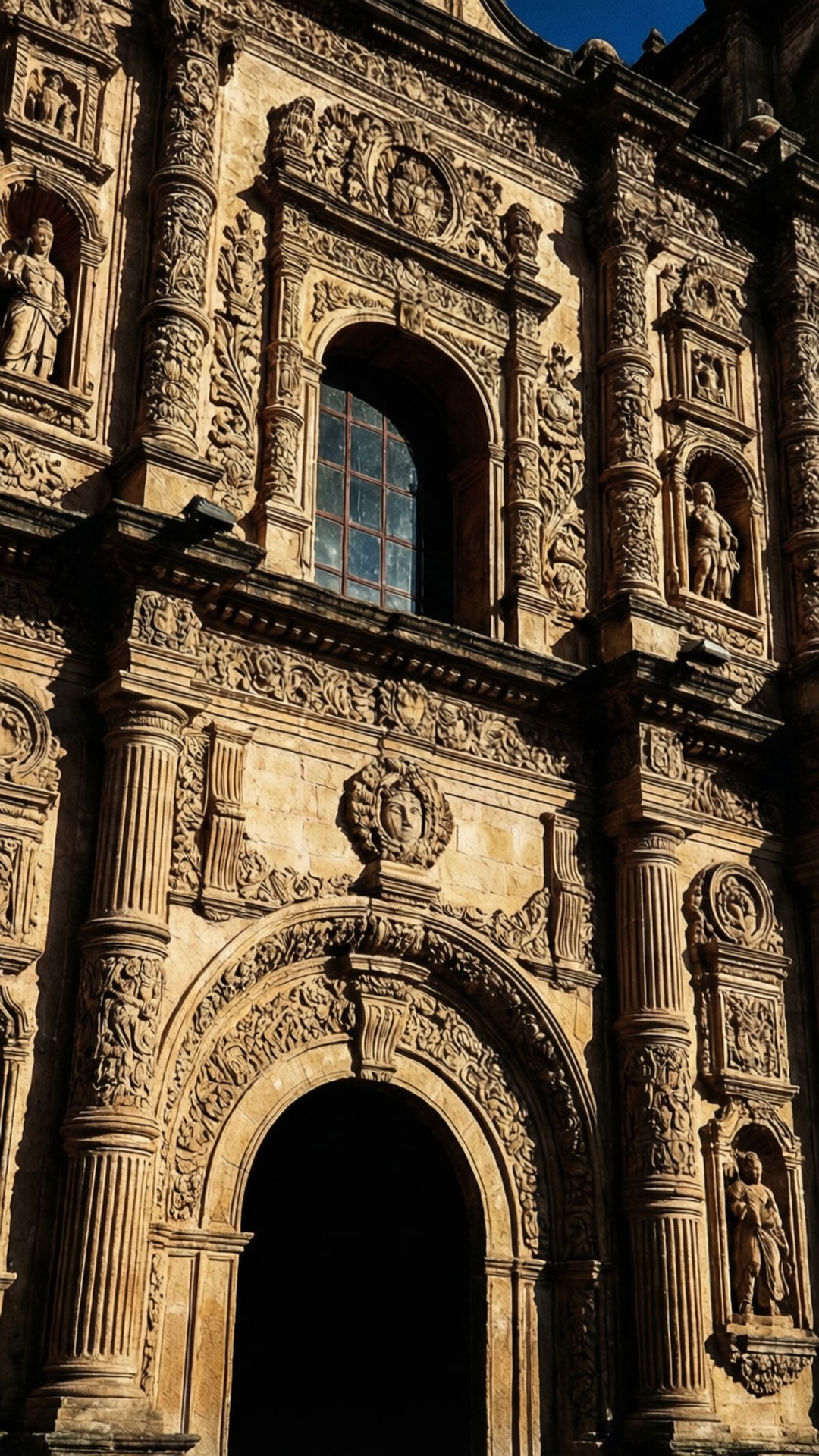 San Agustin Church Detail 壁紙 — 陽光照射的石砌立面，華麗的巴洛克建築，帶有精緻雕刻、雕像和拱形窗戶。