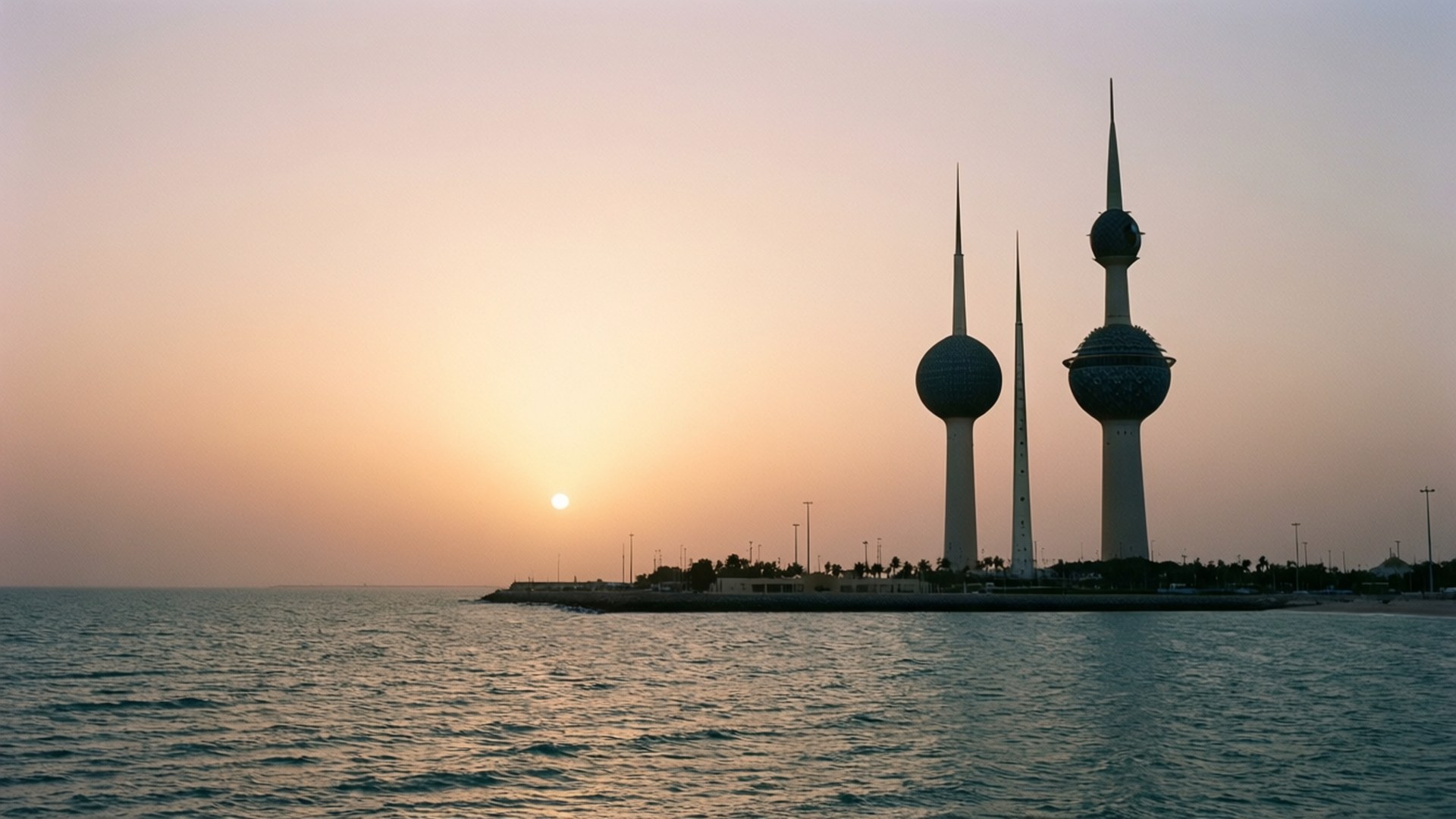 Sunrise Over Kuwait Towers 壁紙 — 日落時分，科威特塔的剪影映襯在平靜的海面上，溫暖的金色天空。