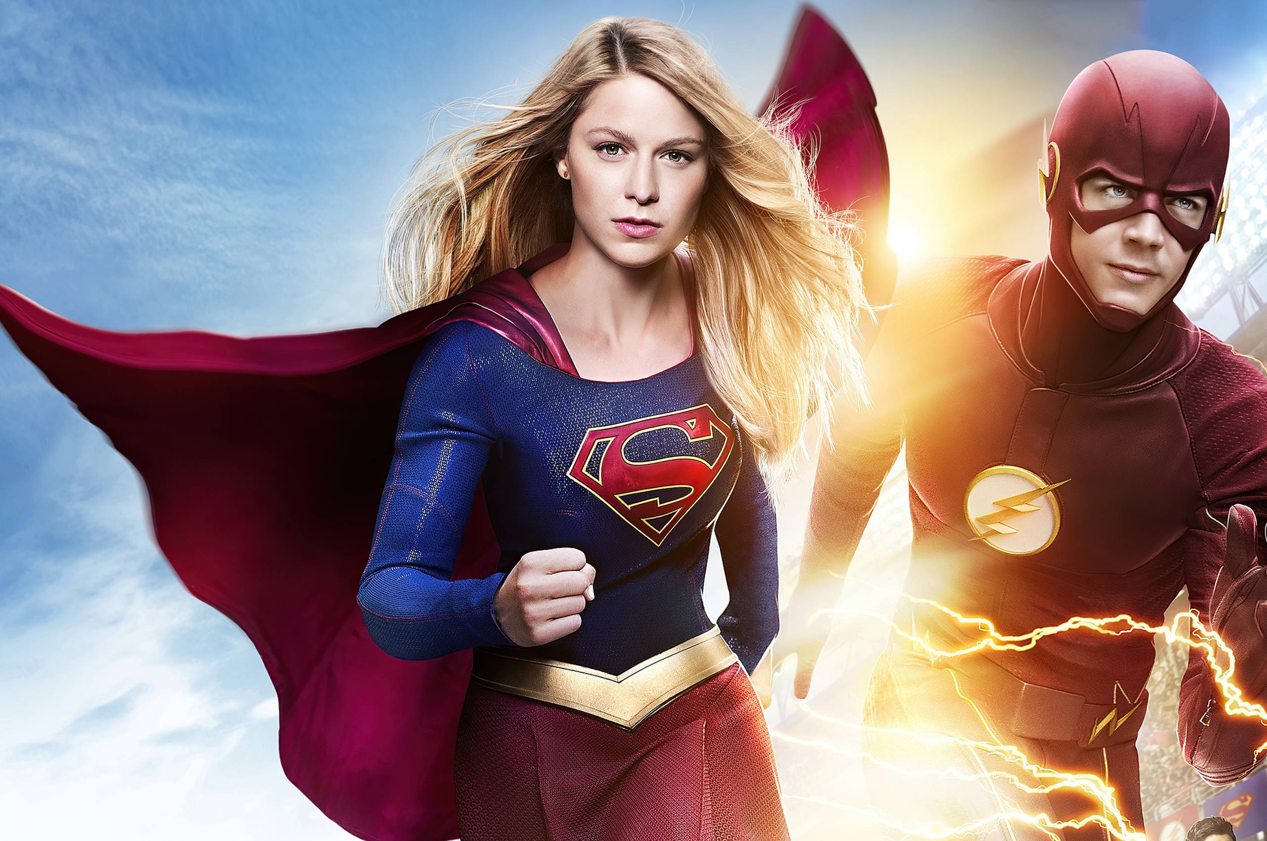 Supergirl 桌布 壁紙 — Supergirl 和 The Flash 英雄般地站在明亮的天空下，閃電在他們周圍劈啪作響。