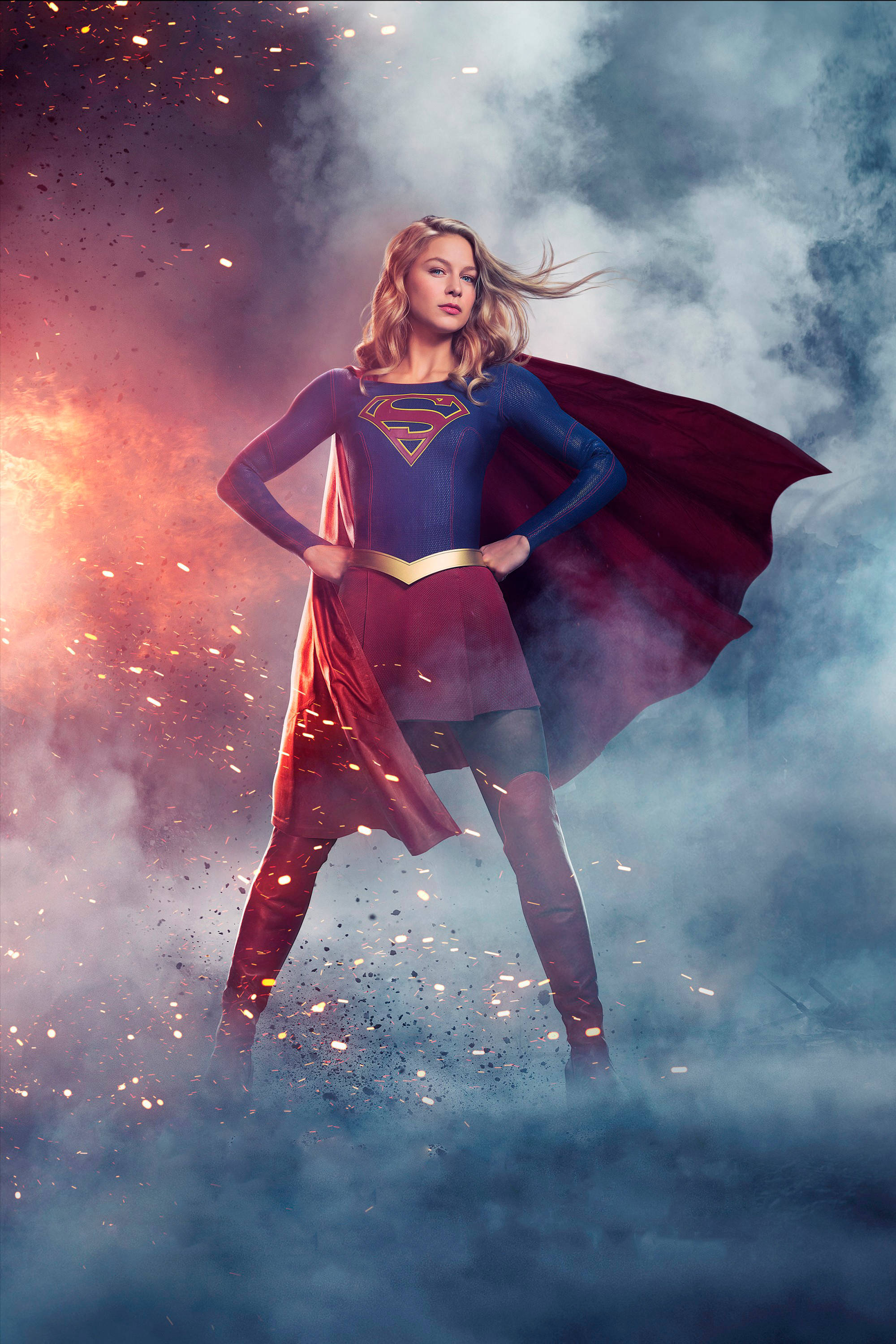 Melissa 桌布 壁紙 — Supergirl 自信地穿著藍色和紅色的套裝，站在火花和旋轉的煙霧中。