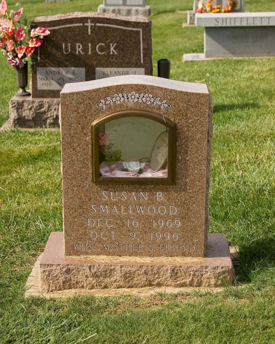 Tombstone 桌布 壁紙 — Susan B. Smallwood 的花崗岩墓碑，位於陽光普照的墓地，配有鮮花和綠草。