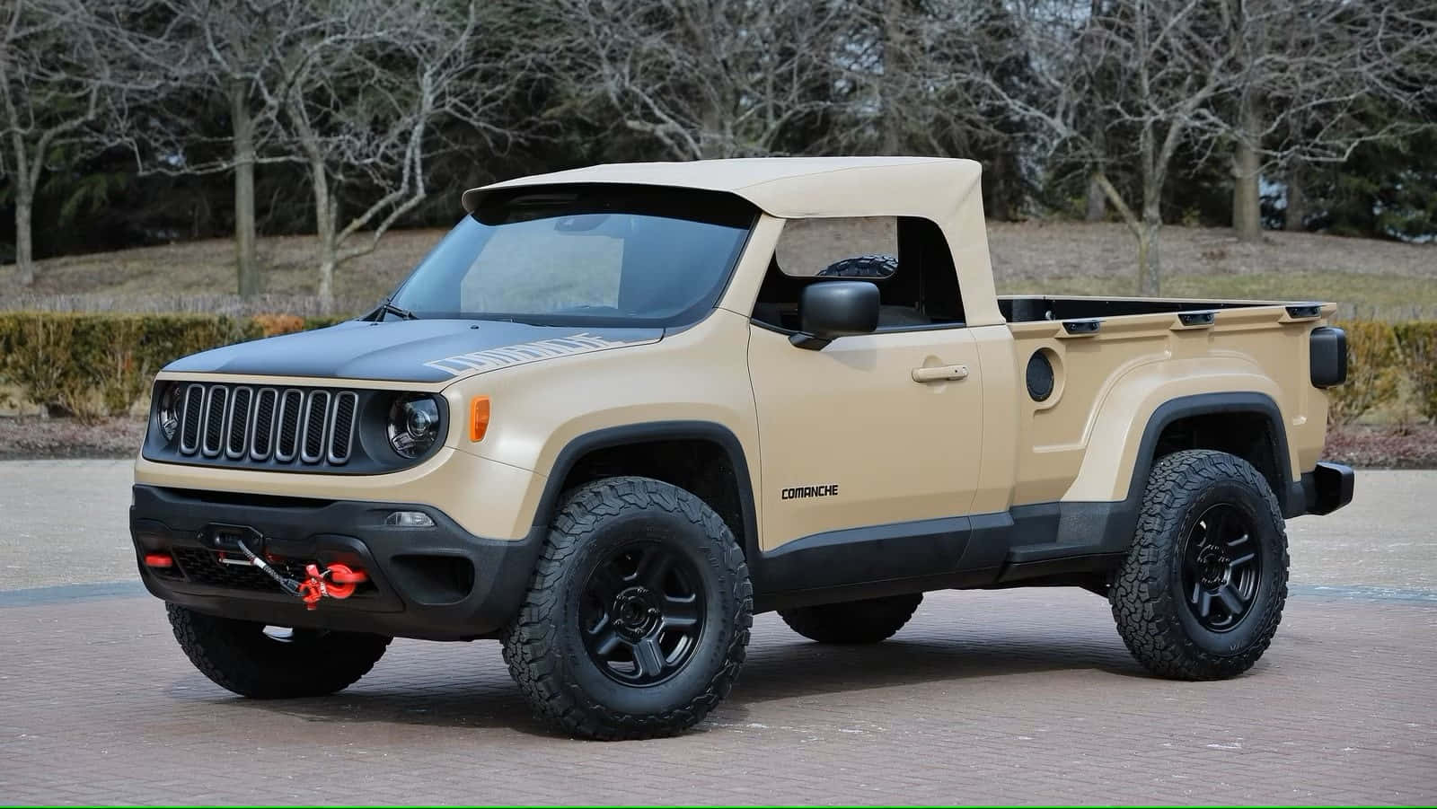 Jeep Comanche 桌布 壁紙 — 一輛棕褐色和黑色的Jeep Comanche皮卡車，配備大型越野輪胎，停放在磚砌車道上，周圍是光禿禿的樹木。