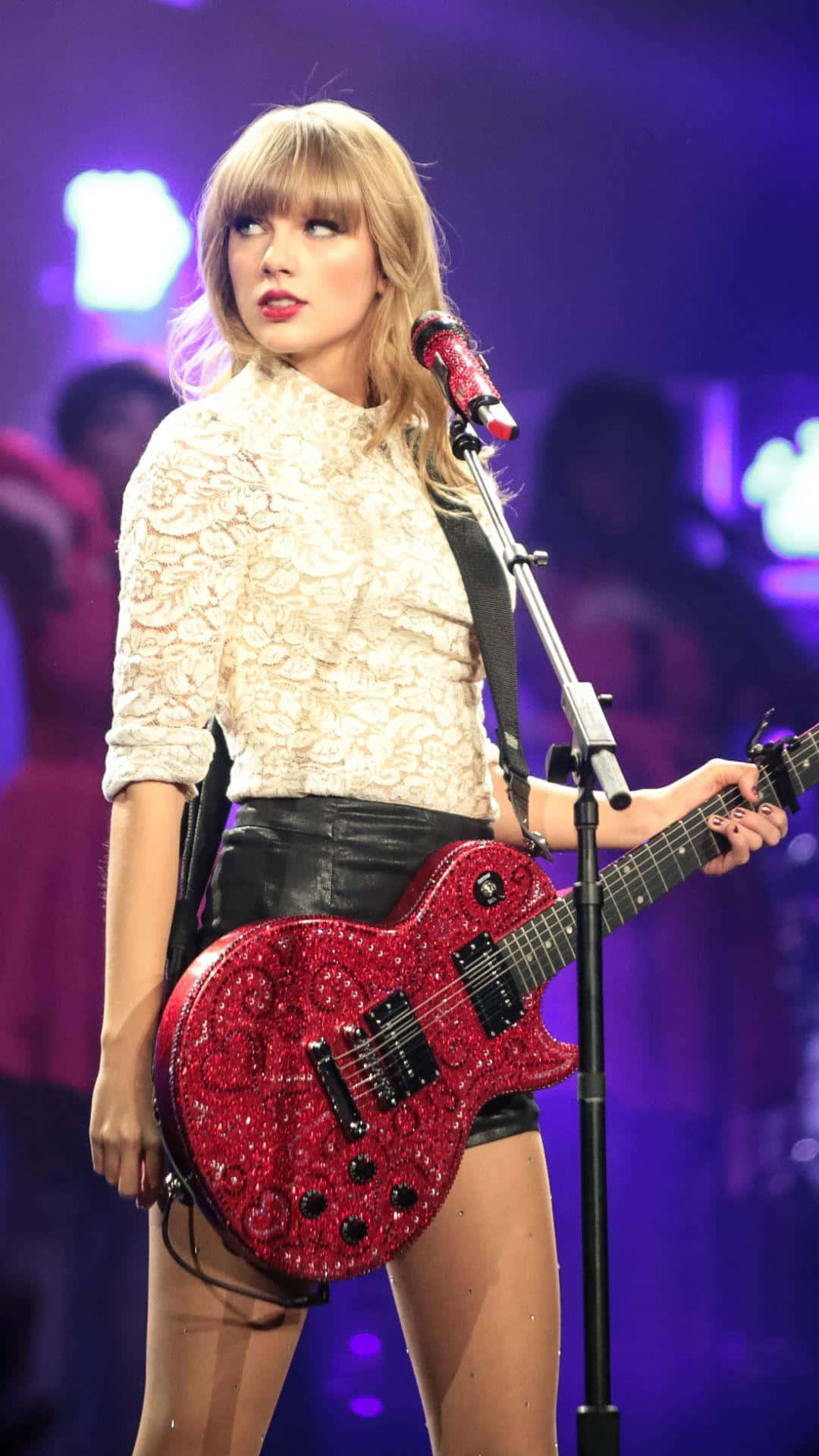 Taylor Swift Lover 桌布 壁紙 — Taylor Swift 在紫色舞台燈光下手持閃亮紅色電吉他表演。