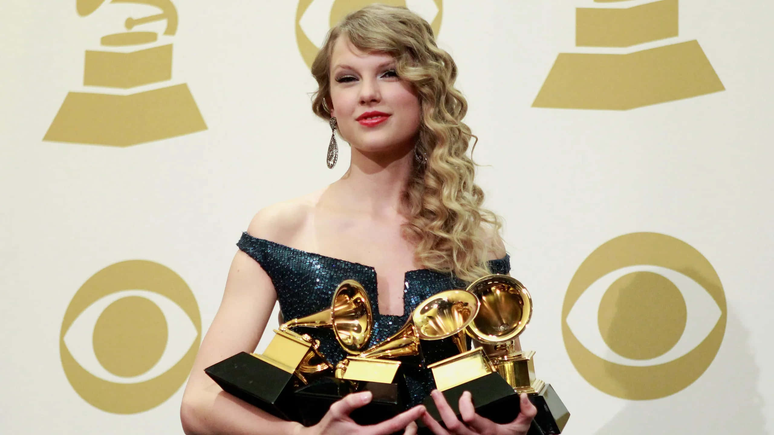 Monochrome 桌布 壁紙 — Taylor Swift 微笑著手持多個葛萊美獎，背景為金色標誌。