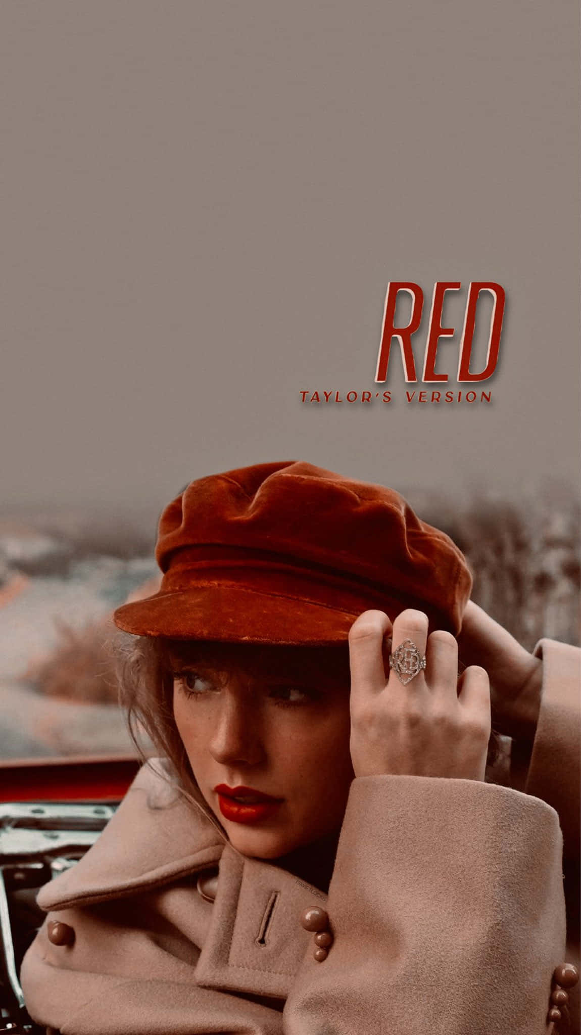 泰勒絲 桌布 壁紙 — Taylor Swift 戴著紅色天鵝絨帽和穿著米色外套，在印有 'RED TAYLOR'S VERSION' 文字的復古車旁若有所思地凝視。