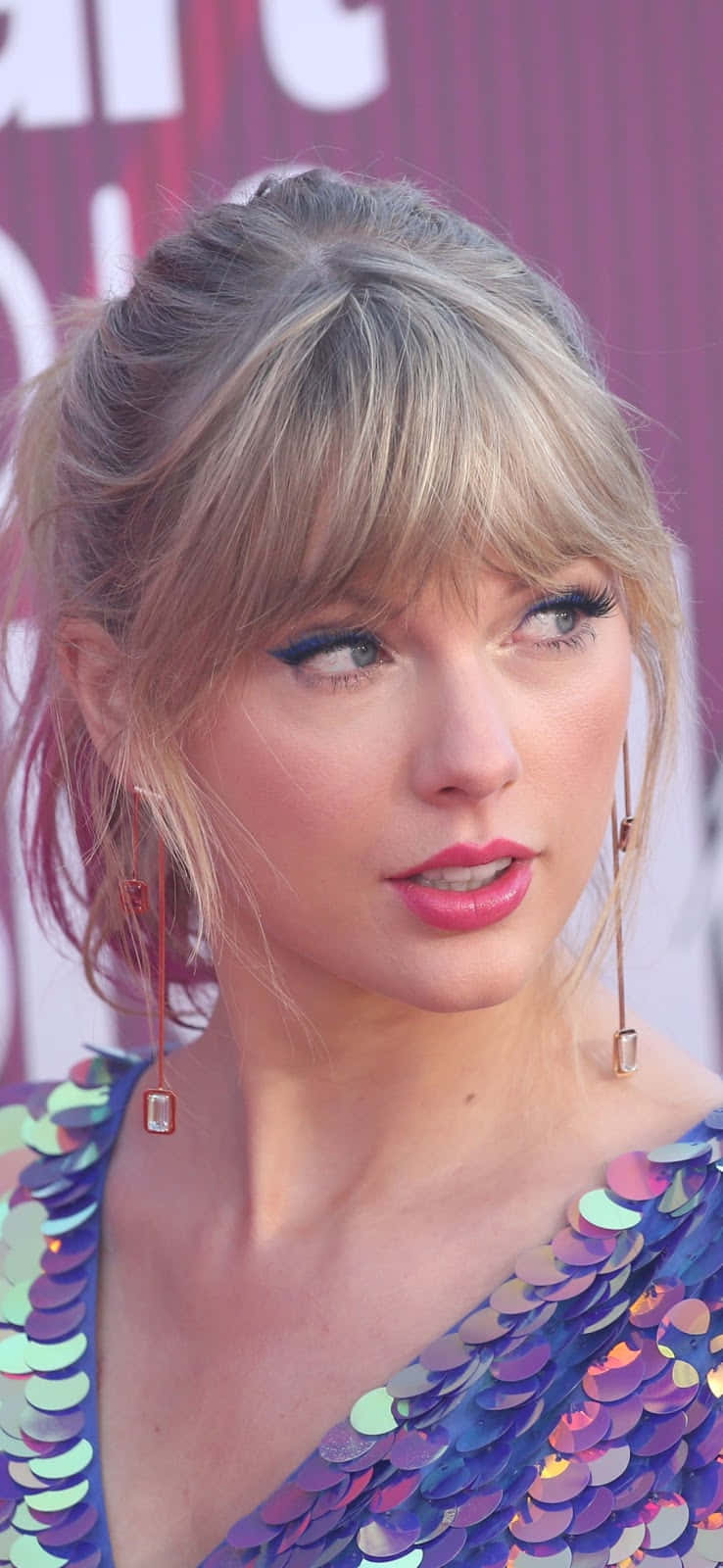 泰勒絲 桌布 壁紙 — Taylor Swift 身穿閃亮紫色亮片連衣裙，在粉紅色背景下側視。