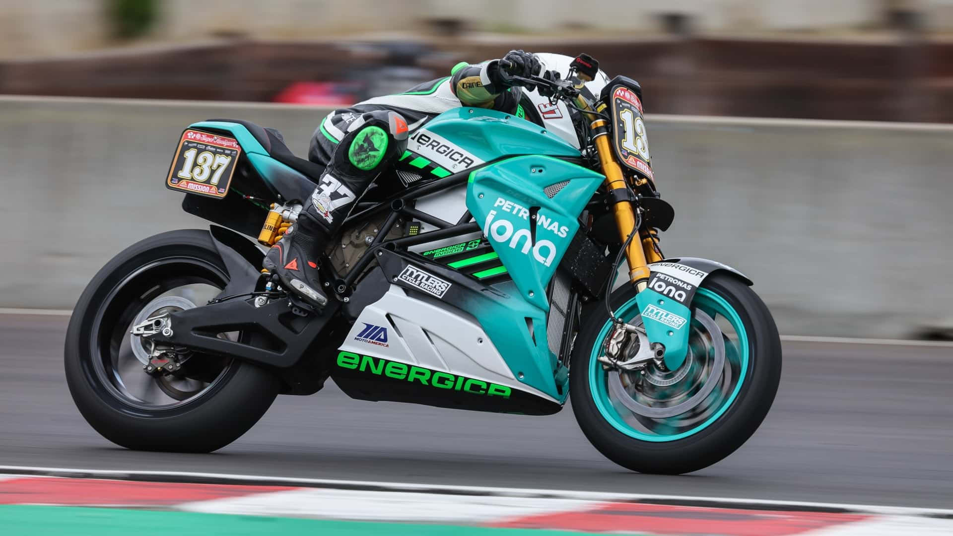  壁紙 — 一輛青綠色和白色的 Energica 電動摩托車，車手編號 137，在紅白相間的路緣賽道上疾馳。