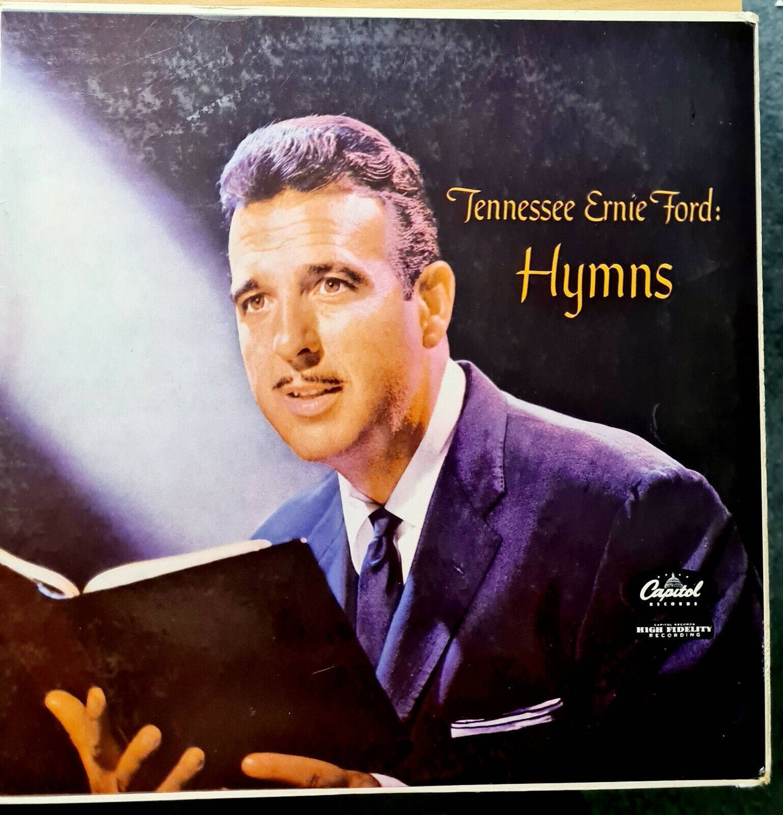 Album Cover 桌布 壁紙 — Tennessee Ernie Ford 身穿深色西裝，在黑色背景的戲劇性聚光燈下手持一本打開的讚美詩集。
