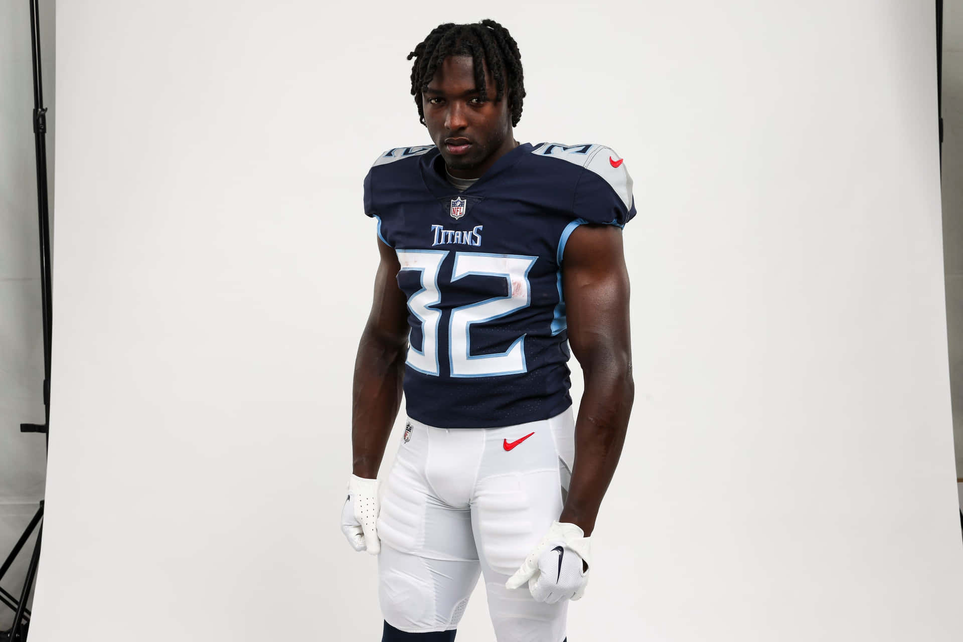  壁紙 — 一位田納西泰坦隊的NFL美式足球員，身穿32號球衣，在攝影棚內自信地站立，穿著全套制服。