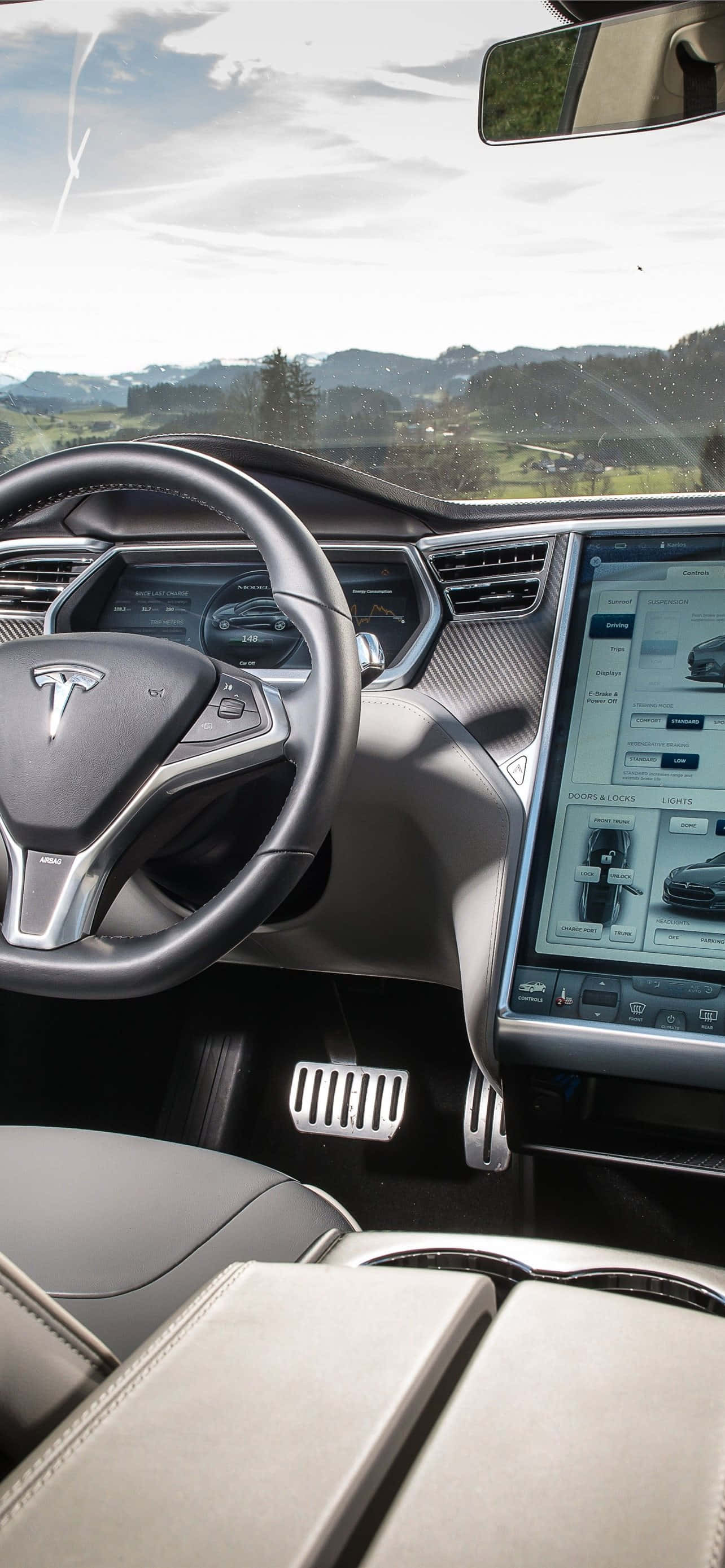 Inside Car 桌布 壁紙 — Tesla 車廂內部視圖，展示時尚儀表板和觸控顯示屏，擋風玻璃外可見風景優美的山景。