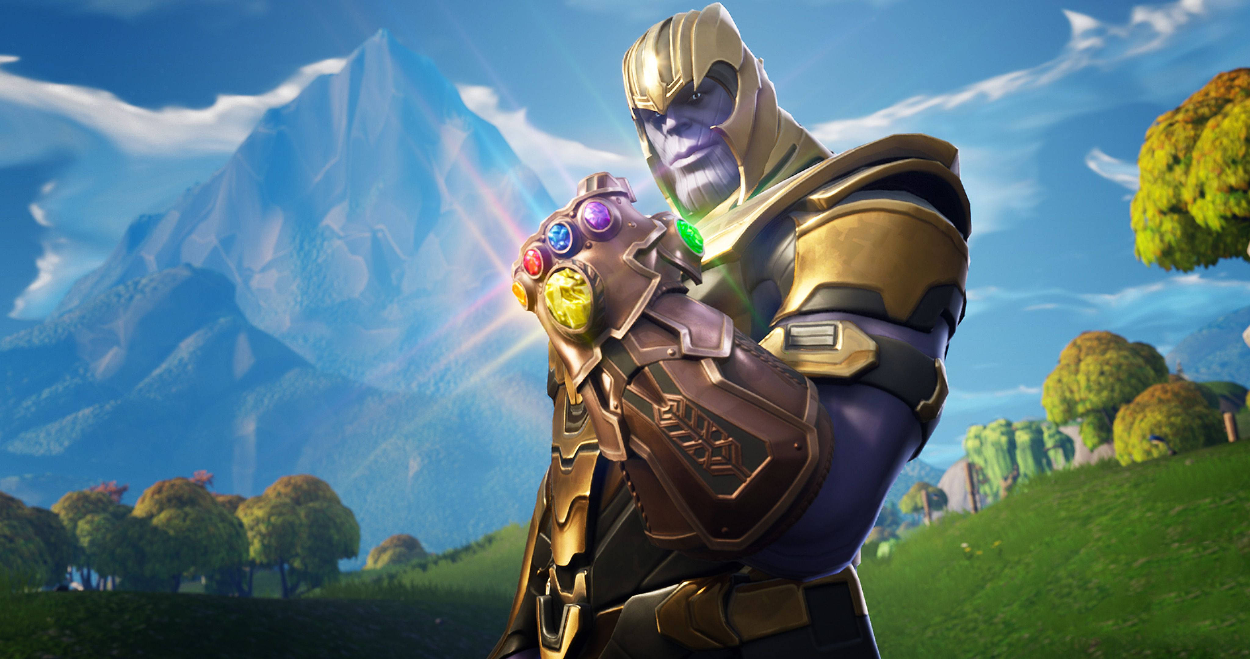 漫威 桌布 壁紙 — Thanos 站在色彩繽紛的田野中，手持發光的無限手套，背後是雄偉的山脈，頭頂是明亮的藍天。