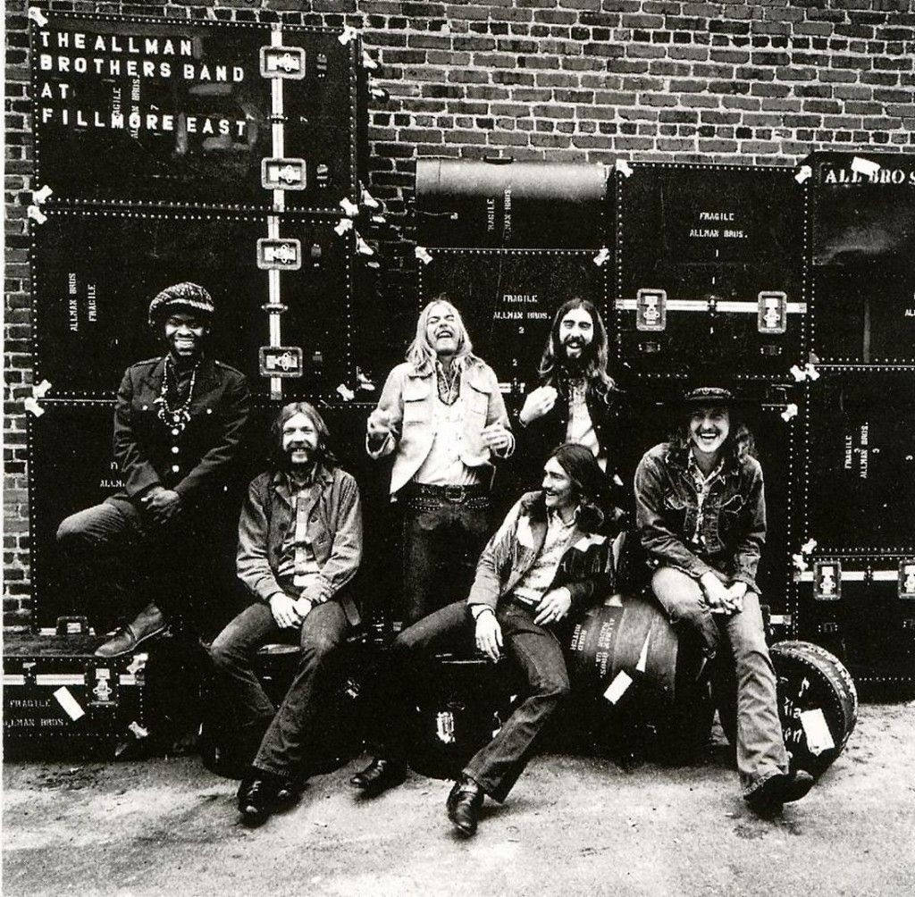 band 桌布 壁紙 — The Allman Brothers Band 在磚牆前面，在他們有標籤的設備箱前面開心地擺姿勢。