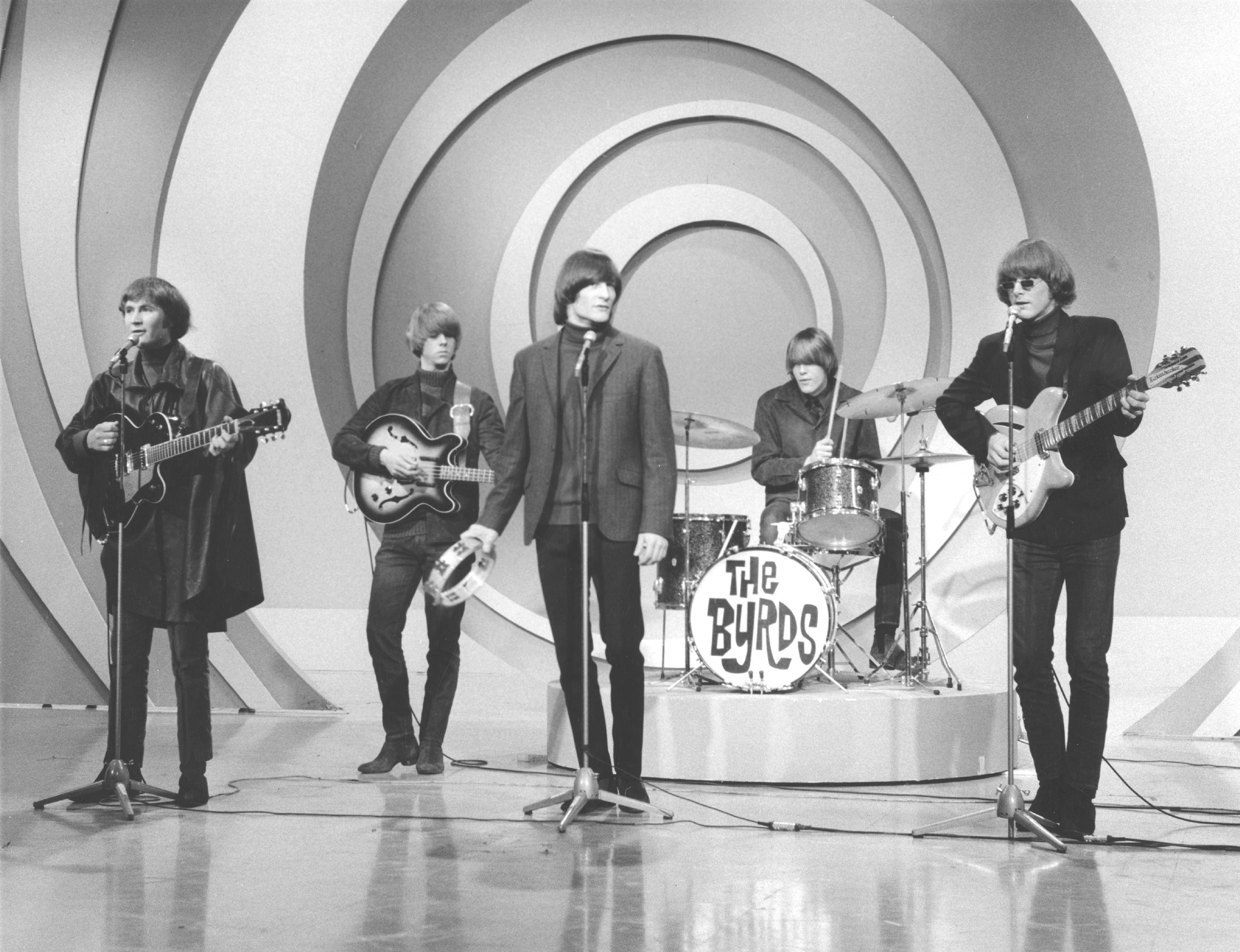 岩石 桌布 壁紙 — The Byrds 在黑白背景下表演，背景是旋轉的幾何圖案，穿著復古1960年代摩登服裝。