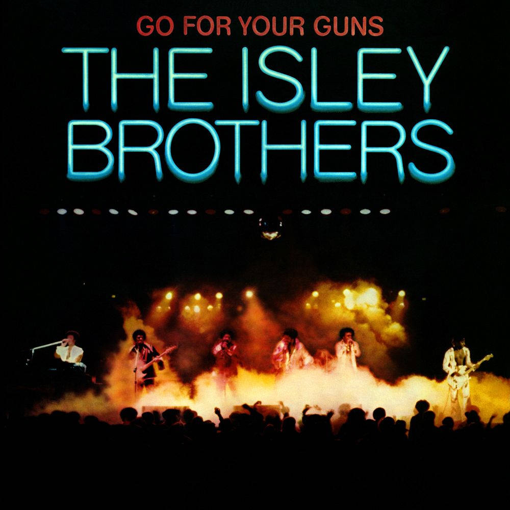 音樂 桌布 壁紙 — The Isley Brothers 在煙霧瀰漫的舞台上表演，舞台被熾熱的橙色燈光籠罩，下方是發光的霓虹文字。