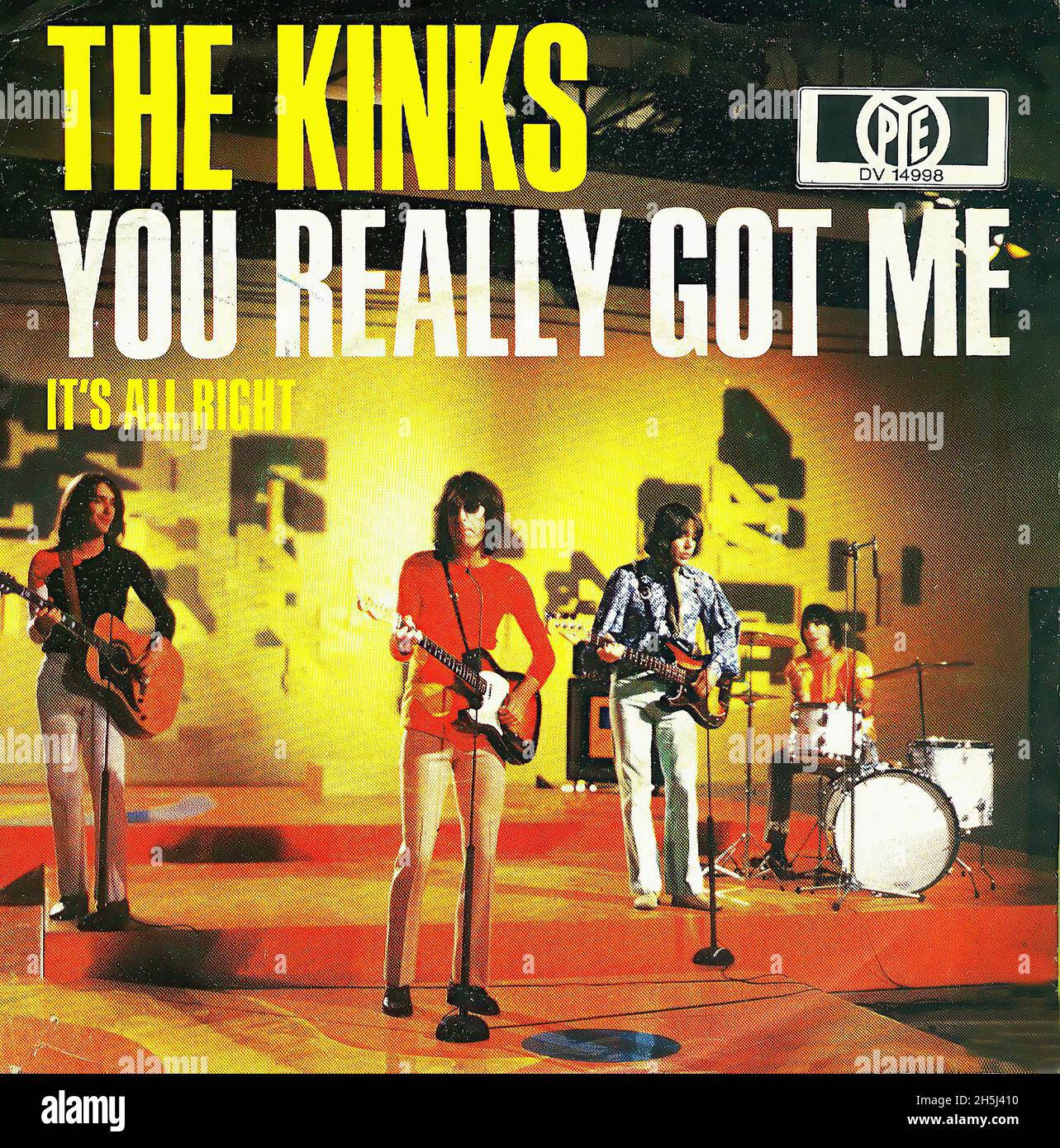 Retro 桌布 壁紙 — The Kinks 在溫暖燈光的舞台上，以吉他和鼓演出，下方有粗體黃色和白色文字。