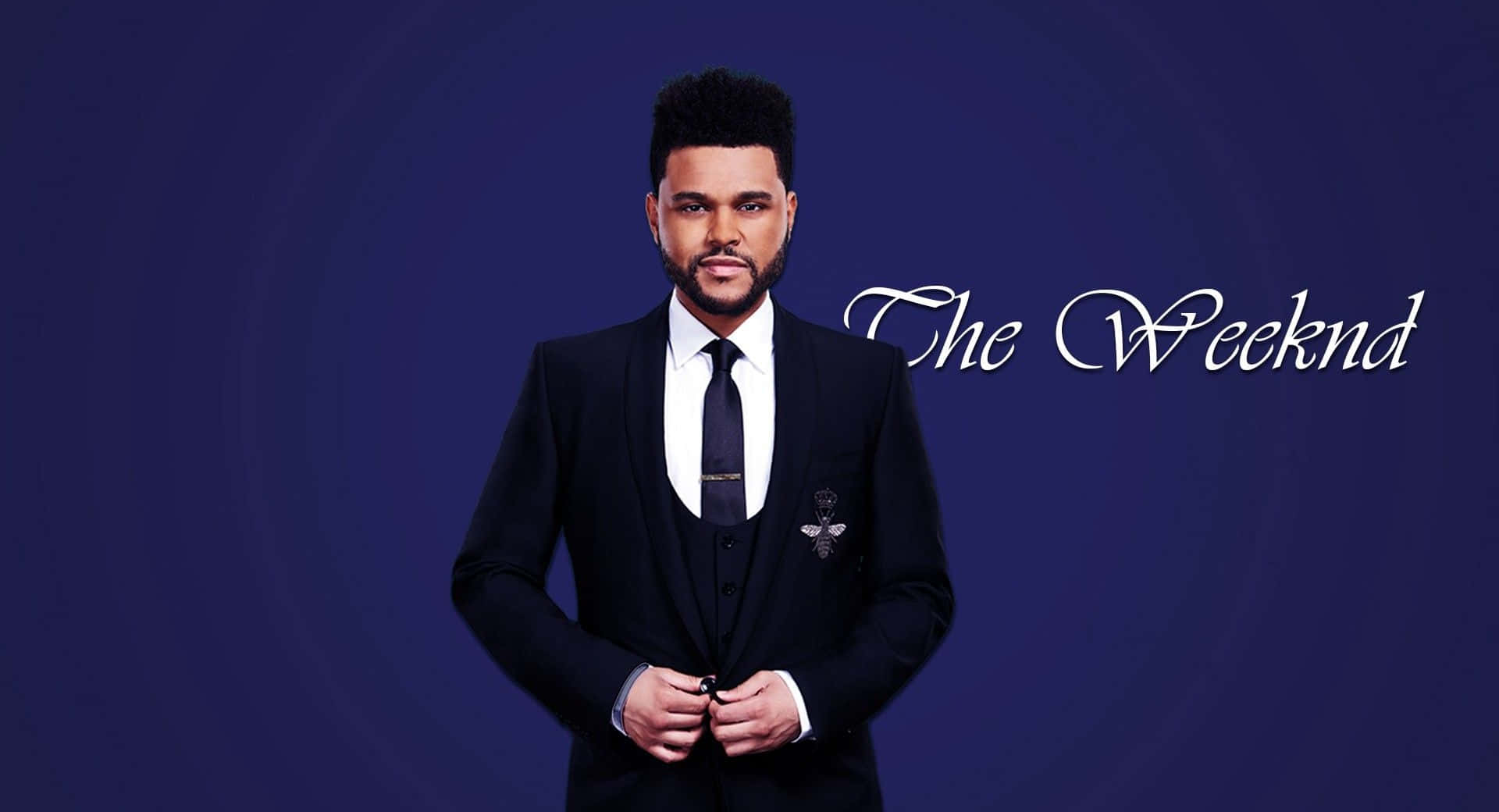 威肯 桌布 壁紙 — The Weeknd 自信地穿著黑色西裝，站在深藍色漸變背景前，他的名字以優雅的白色草書書寫。