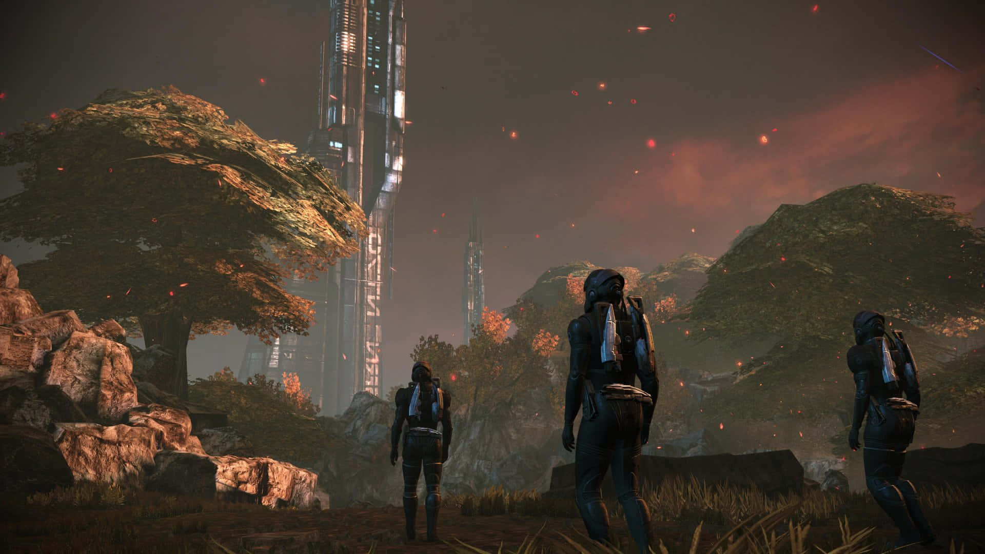 Mass Effect Legendary Edition 桌布 壁紙 — 三個身穿盔甲的身影站在迷霧籠罩的外星景觀中，凝視著火紅天空下高聳的未來主義尖塔。