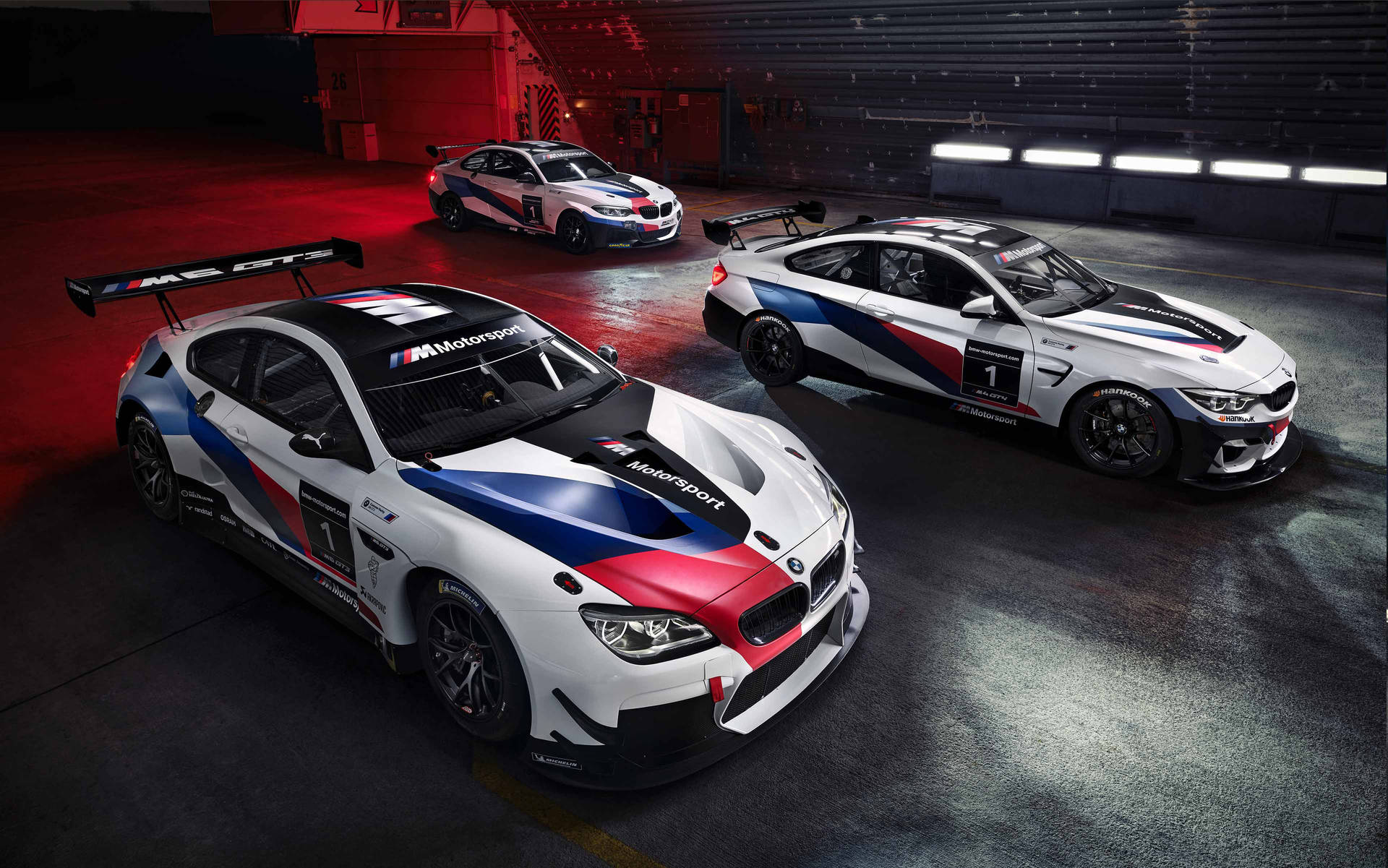 紅色燈光下的車庫裡的三輛BMW賽車。