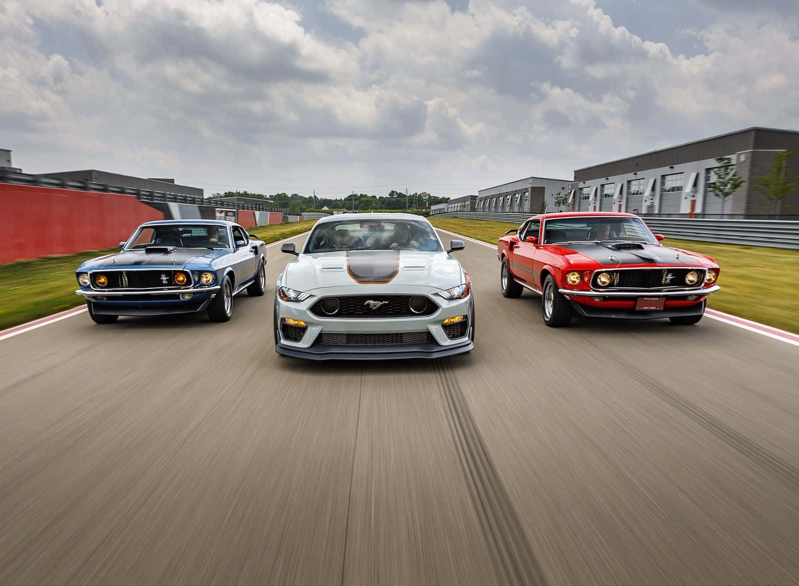Ford Mustang Mach 1 桌布 壁紙 — 三輛經典與現代野馬在陰天下並排於賽道上競速。